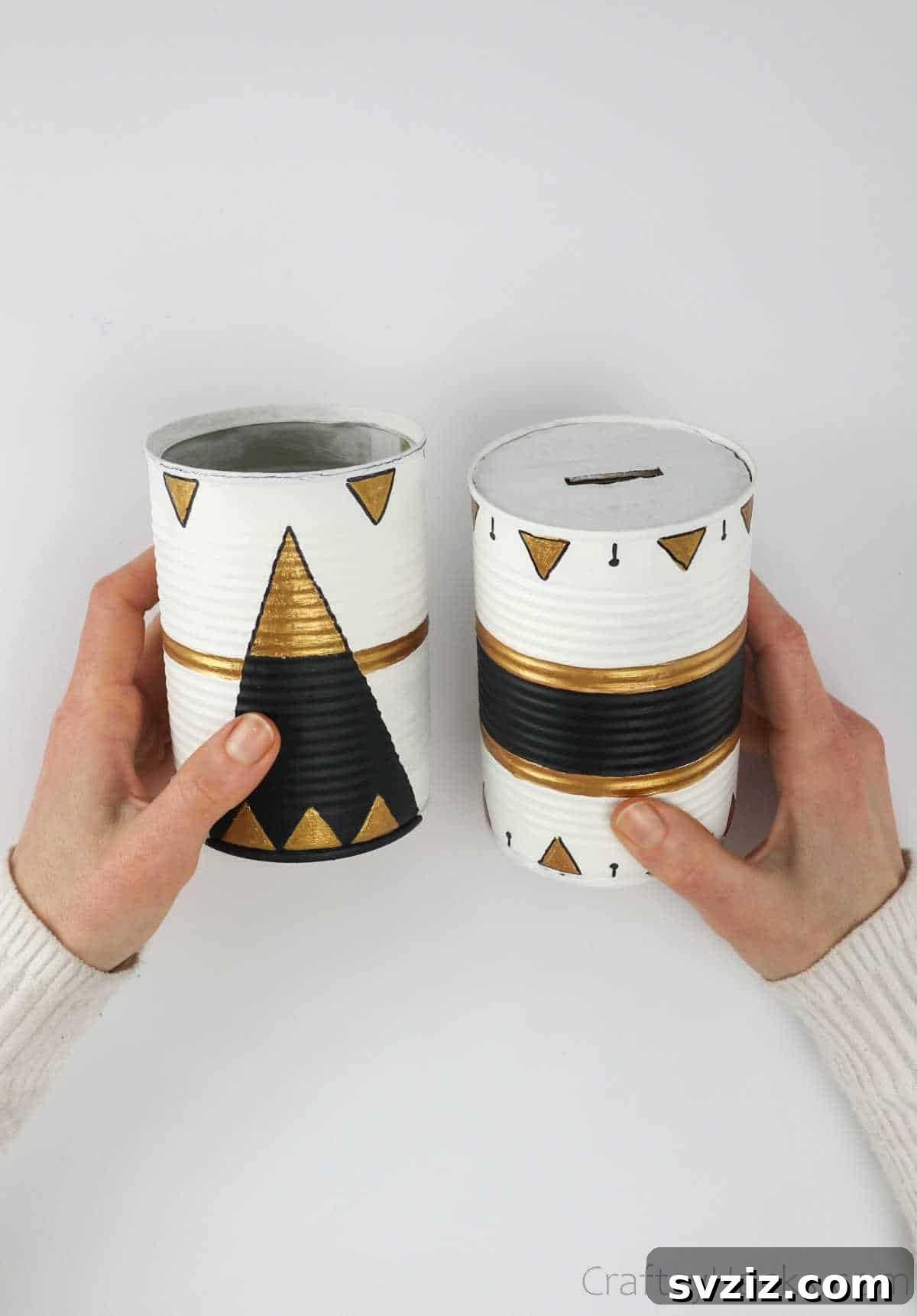 Repurposed Tin Treasures 22 A hand holding two finished, painted upcycled tin cans, ready for use