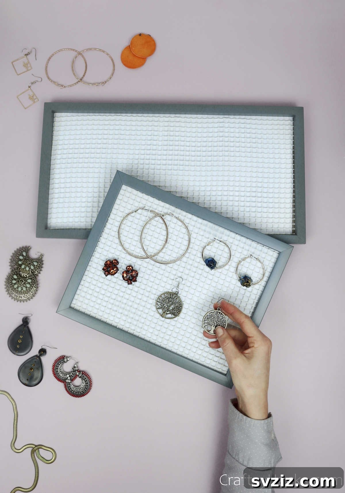 Turn Old Frames into a Chic Earring Organizer 16 Hand placing an earring onto the newly made DIY earring organizer