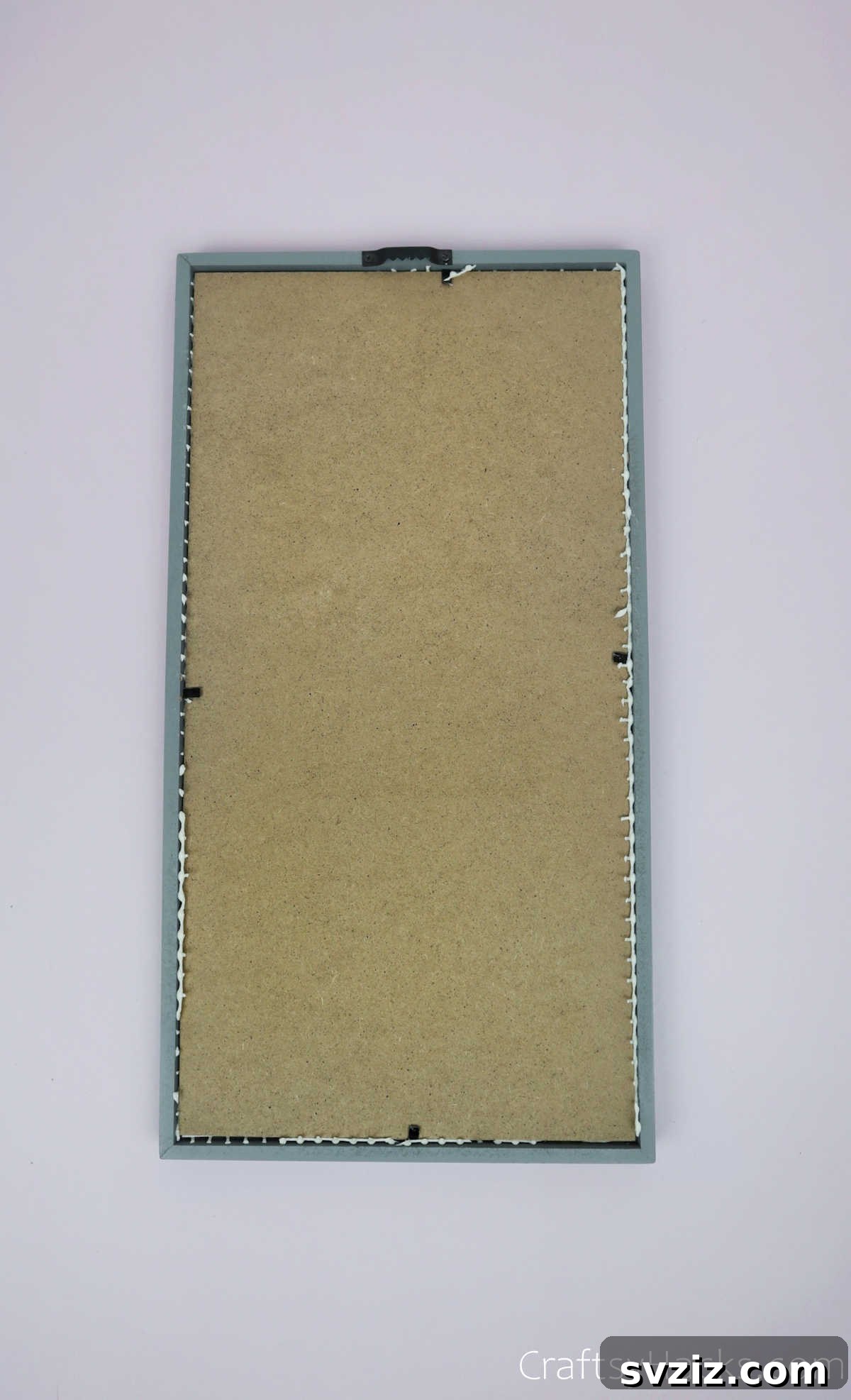 Turn Old Frames into a Chic Earring Organizer 10 Securing the back panel of the photo frame to hold the liner and backdrop in place
