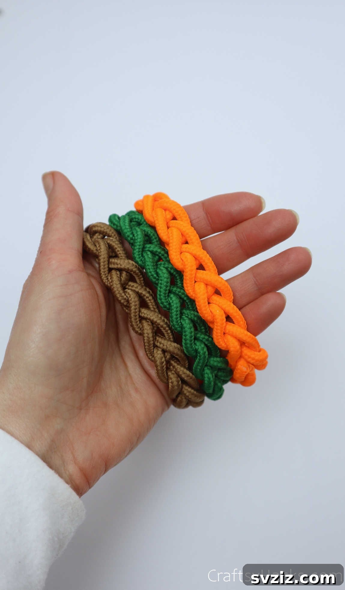 holding brown, green, and orange bracelets