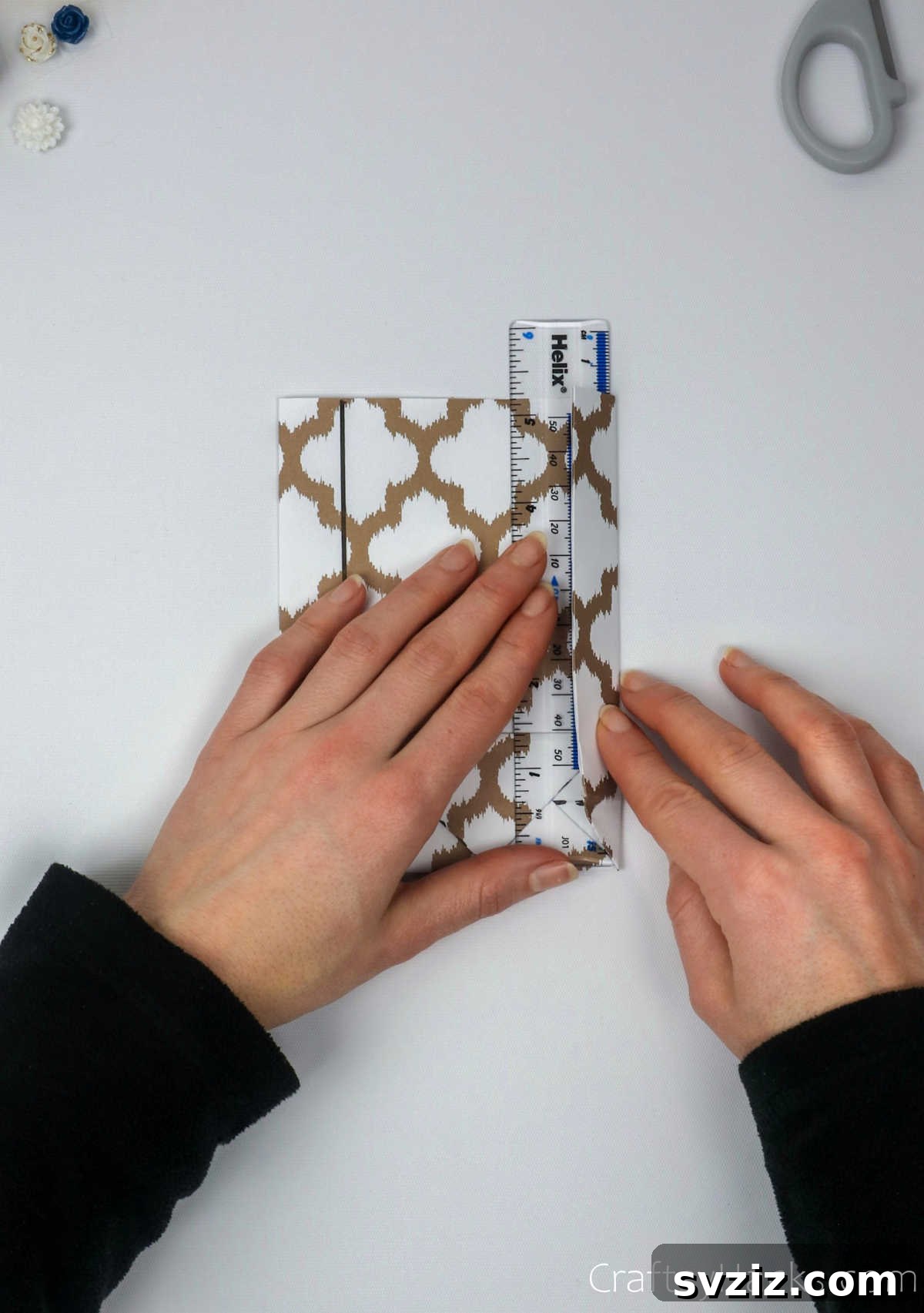 Homemade Touch: Custom Gift Bags 21 A ruler being used to create crisp folds along the marked vertical lines on the paper sides.