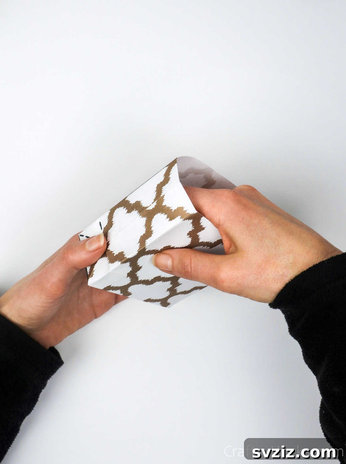 Homemade Touch: Custom Gift Bags 25 A hand gently opening the folded paper to reveal the three-dimensional gift bag shape.