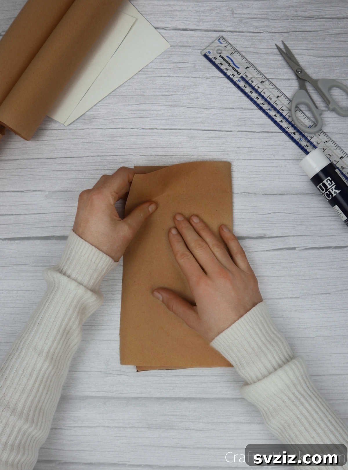 Make Your Journal Cover Unique 11 A notebook, now partially covered in kraft paper, being gently folded shut to create a crease along its spine.