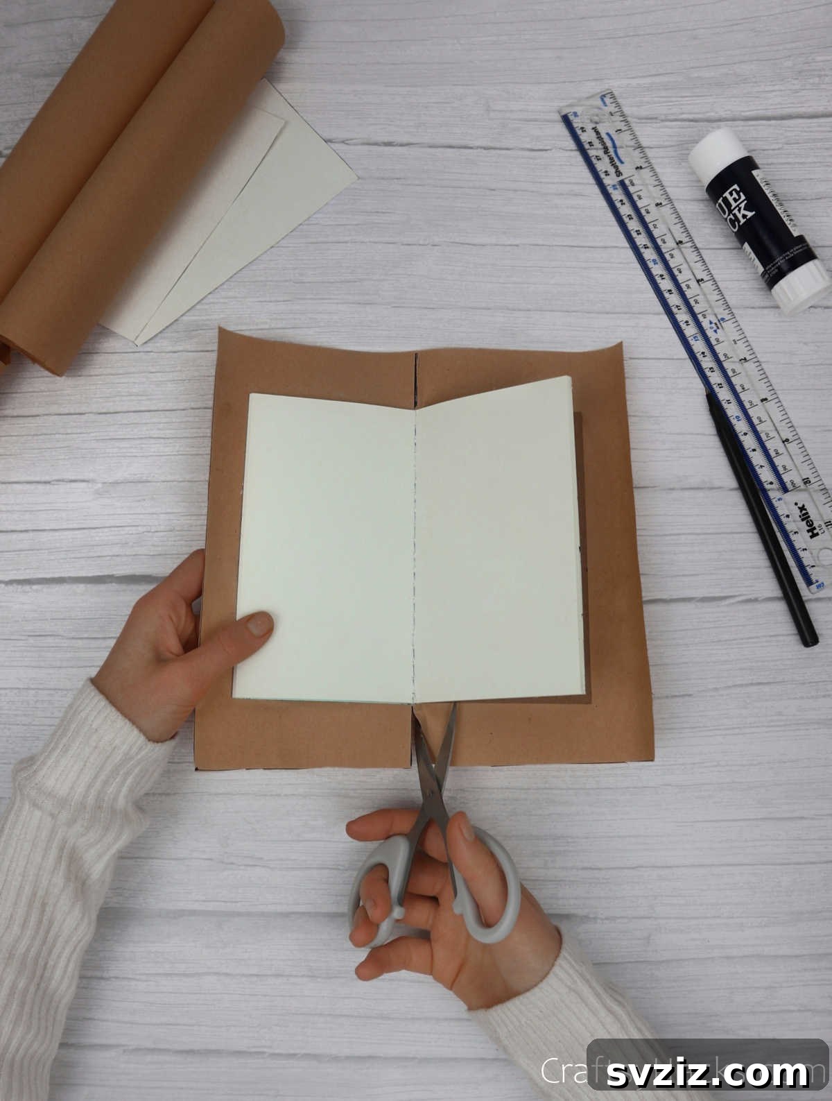 Make Your Journal Cover Unique 12 A pair of scissors making a precise vertical cut into the kraft paper, aligning with the edge of the attached notebook.