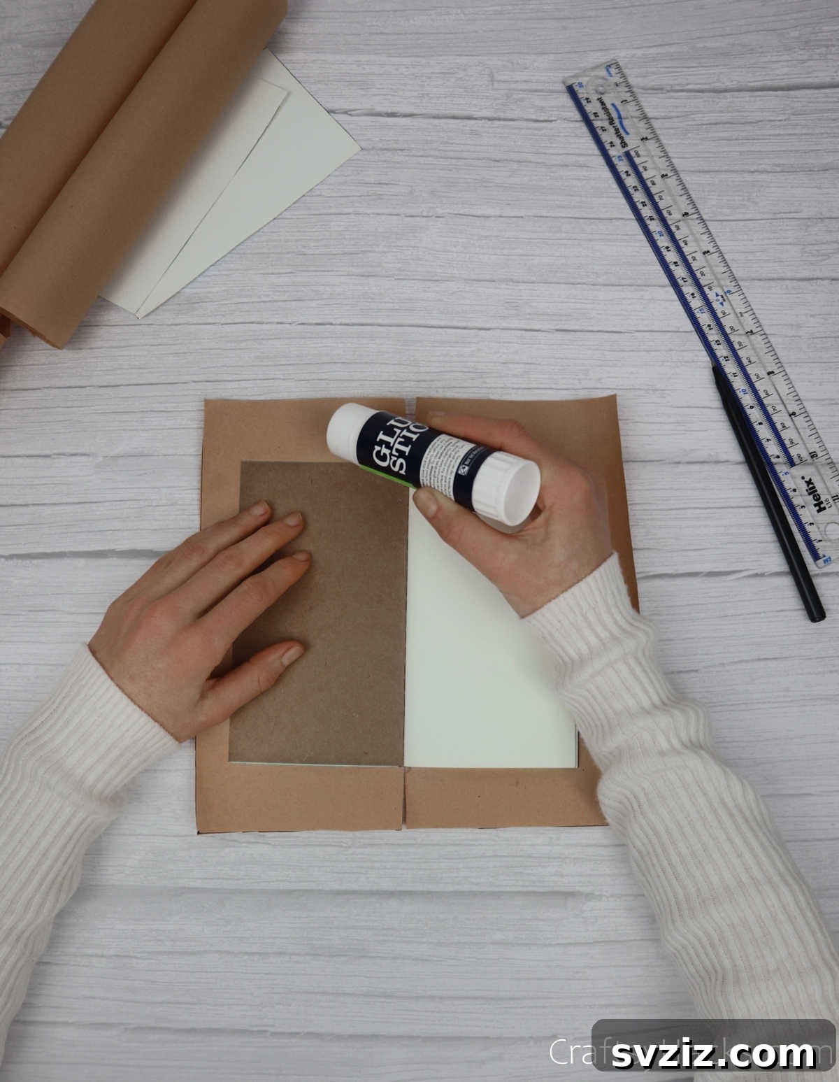 Make Your Journal Cover Unique 14 A glue stick applying adhesive to the edge of the kraft paper, preparing it for folding inwards onto the journal cover.