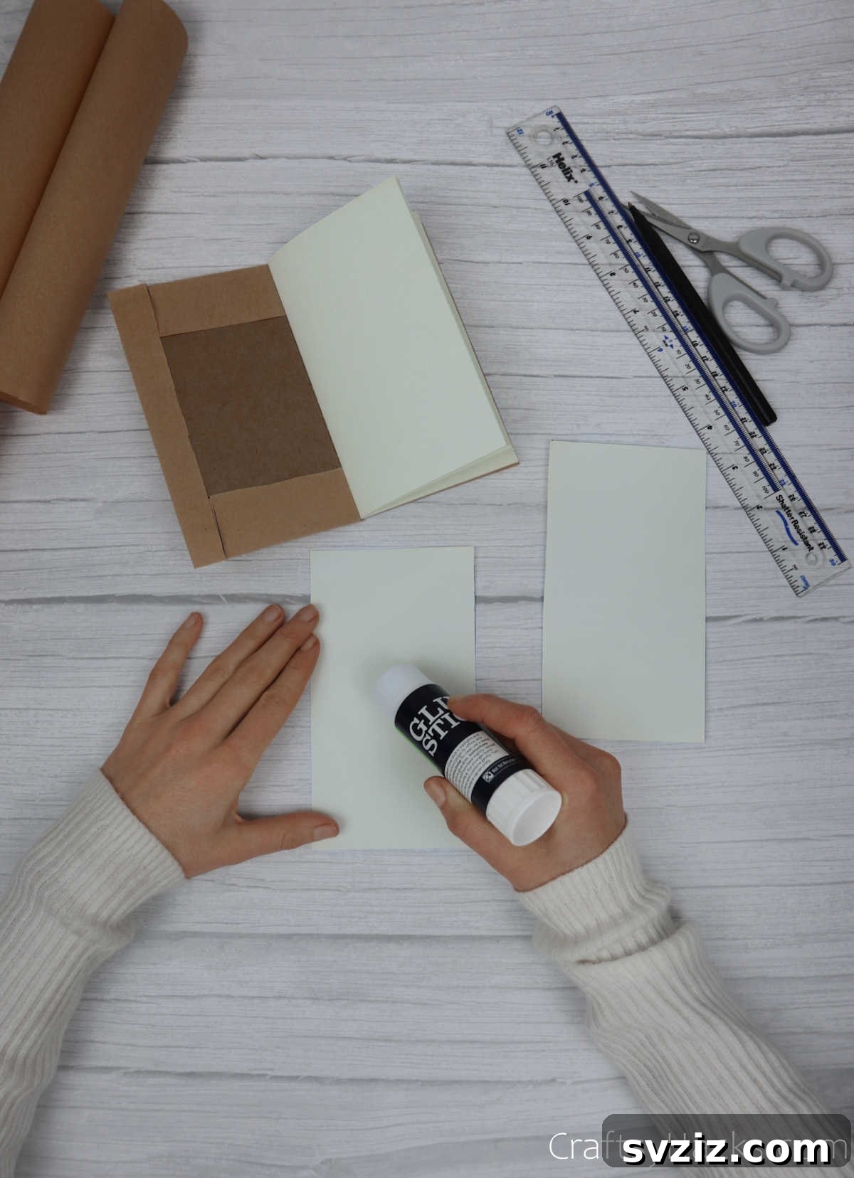 Make Your Journal Cover Unique 16 A glue stick applying adhesive to the back of one of the plain paper rectangles, preparing it to be an inner cover panel.