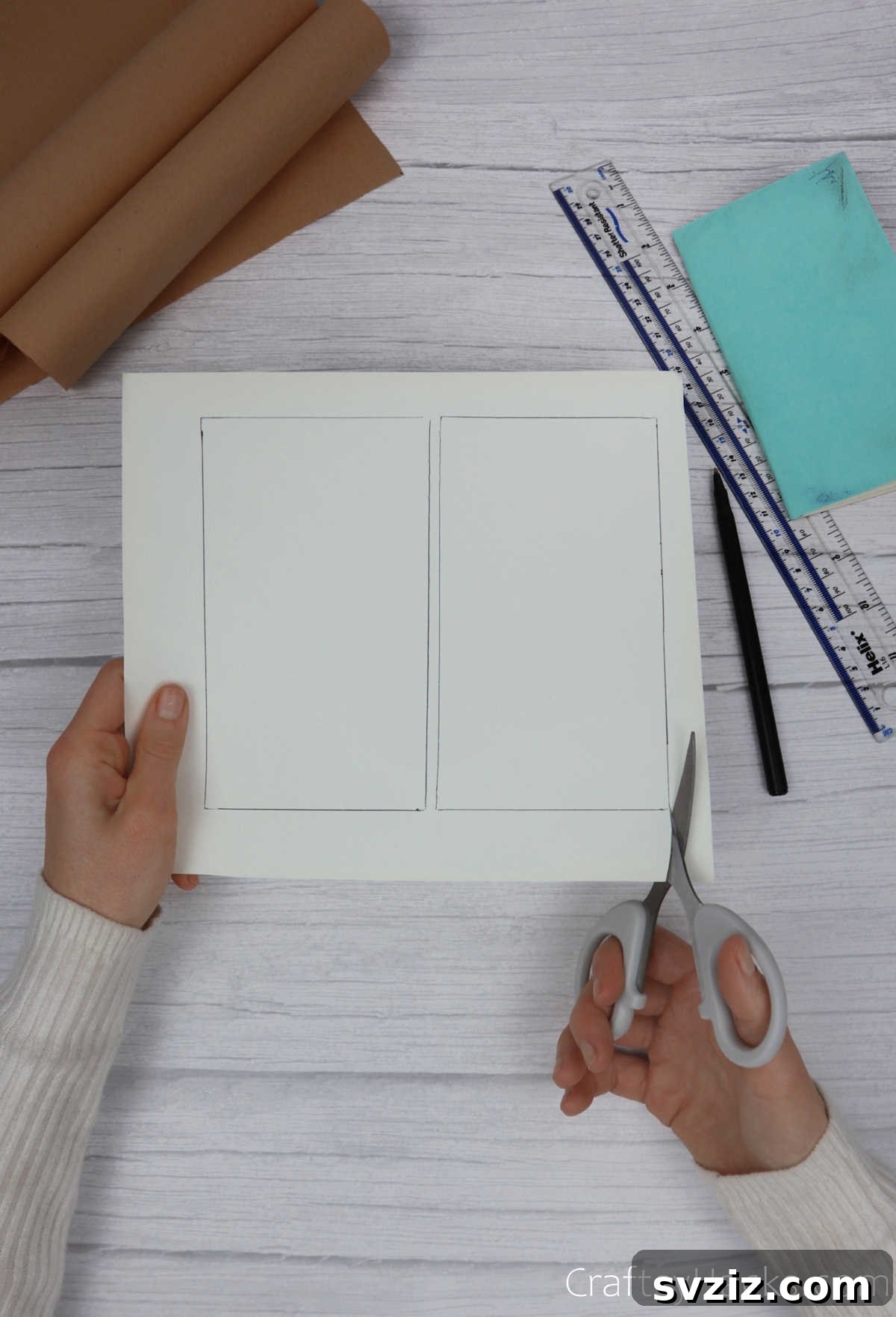 Make Your Journal Cover Unique 8 A hand holding scissors, carefully cutting out a traced rectangle from a plain piece of paper.