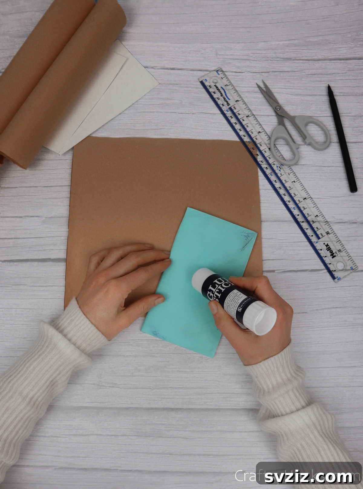 Make Your Journal Cover Unique 9 A glue stick being used to apply adhesive evenly across the back cover of an open notebook.
