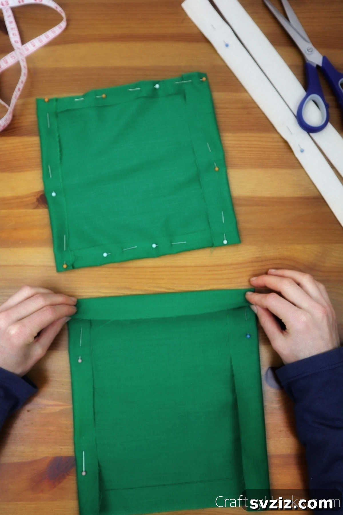 Folded edges of green fabric secured with pins