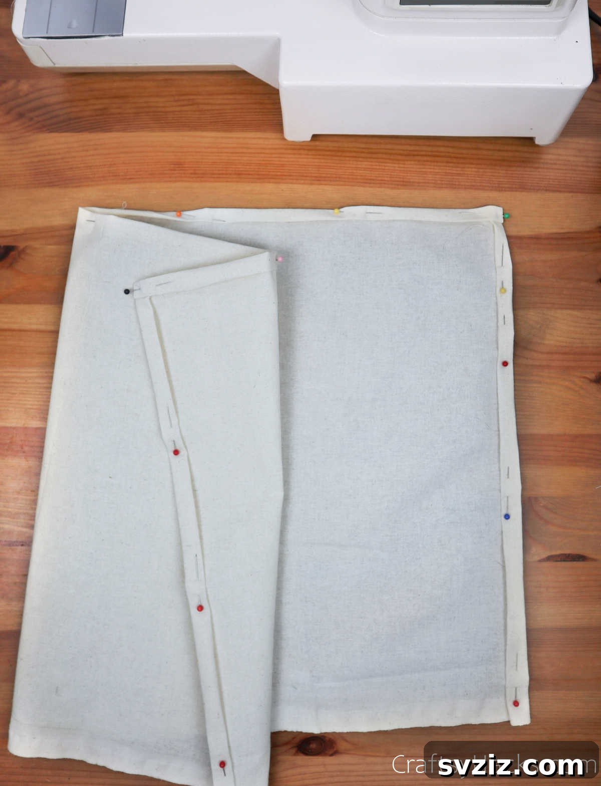 Large white fabric with pinned edges, ready for pocket placement