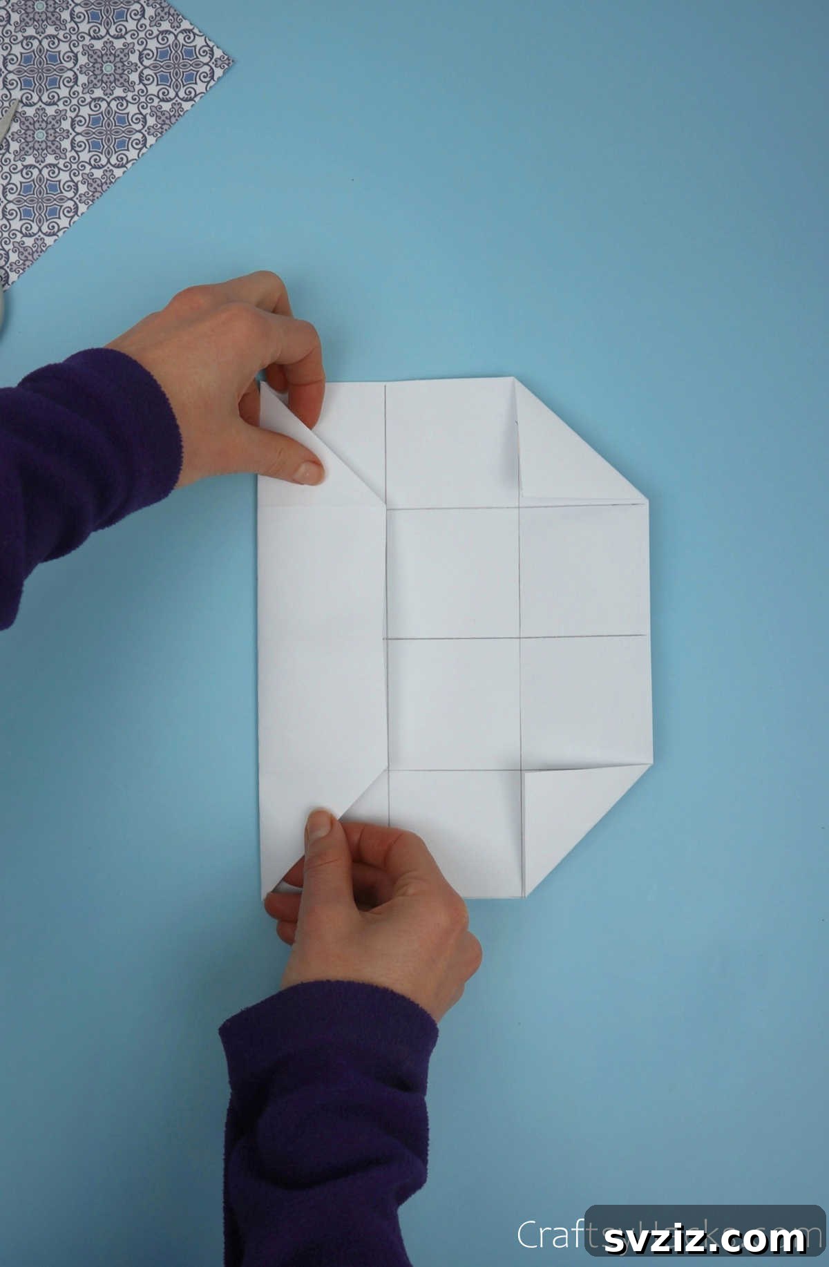 The left side of the paper, with its corner triangle already folded, being brought inwards towards the central vertical crease of the module.