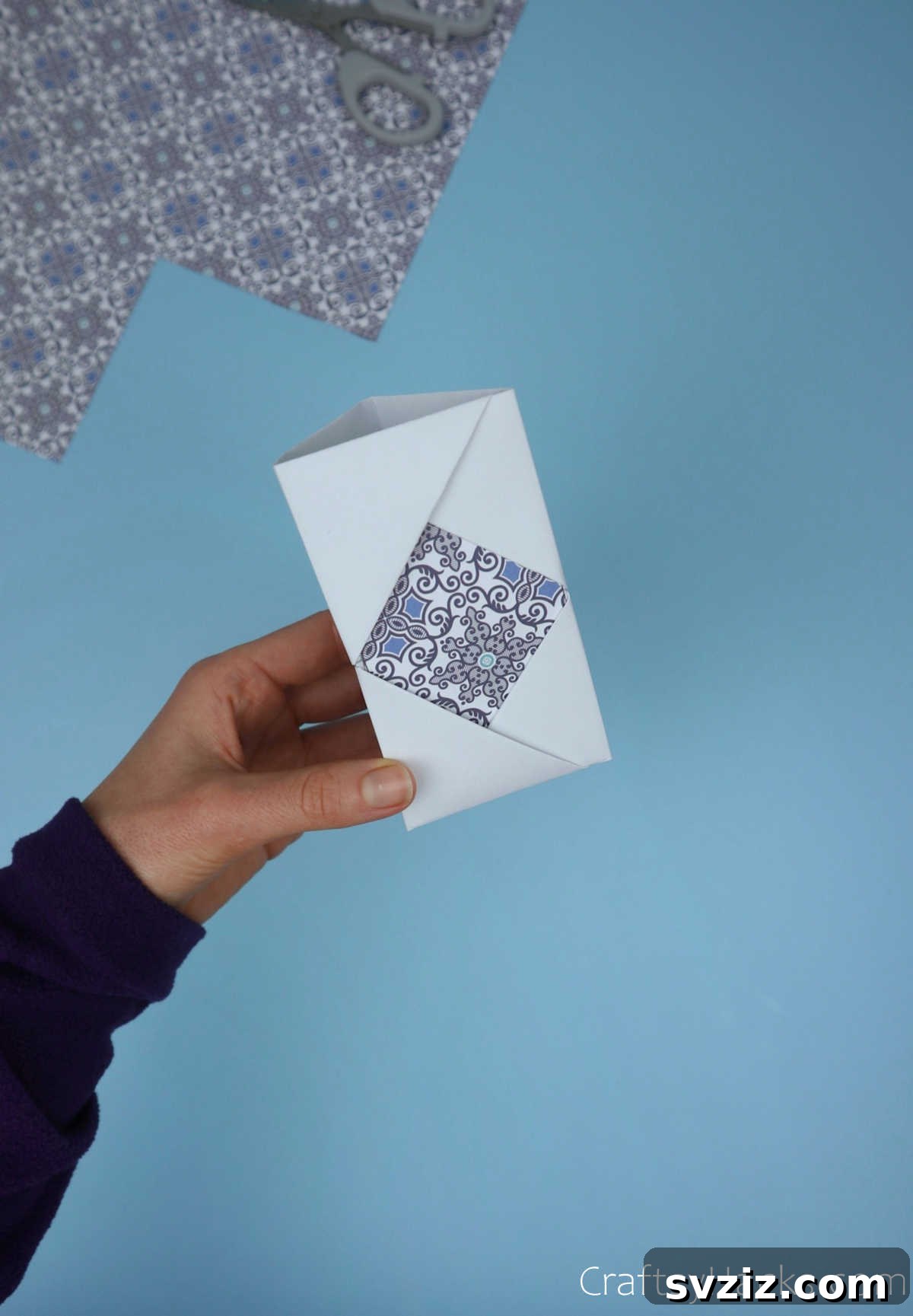 A completed paper module with the decorative patterned paper securely tucked into its diamond-shaped opening, ready for assembly.