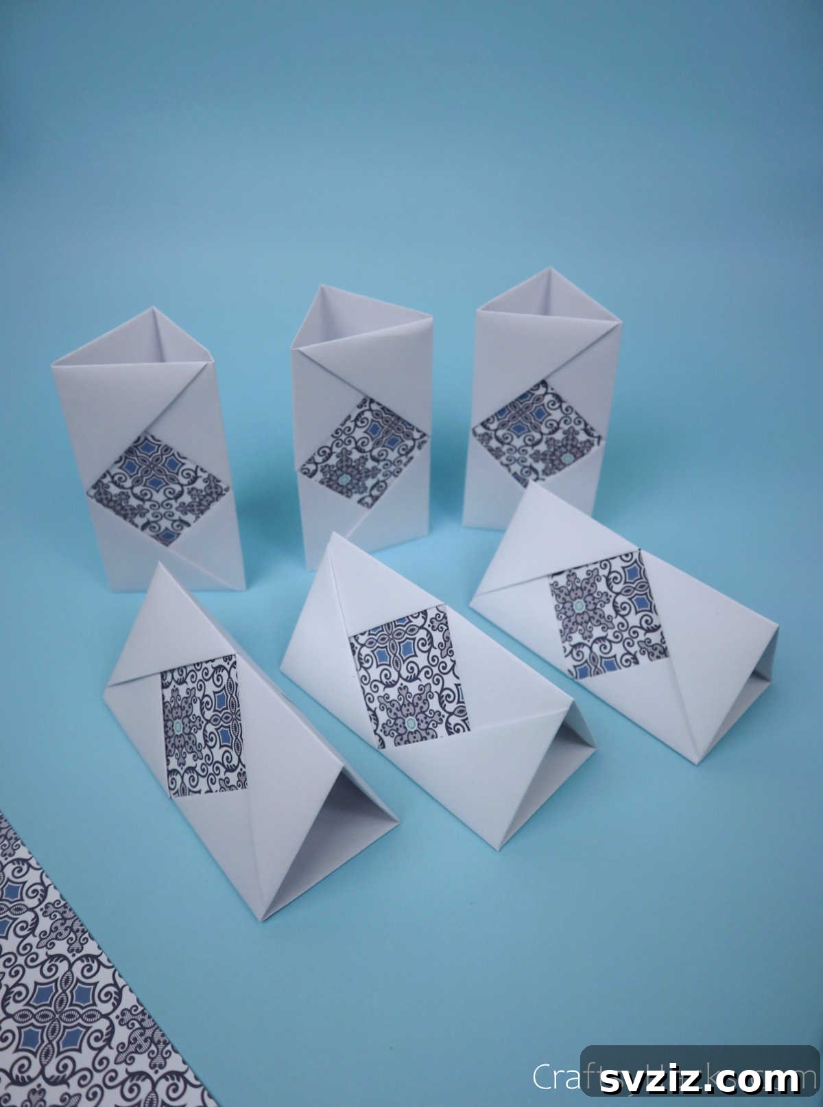 Six identical, neatly folded paper modules laid out side-by-side, perfectly prepared for assembly into a multi-compartment pencil holder.