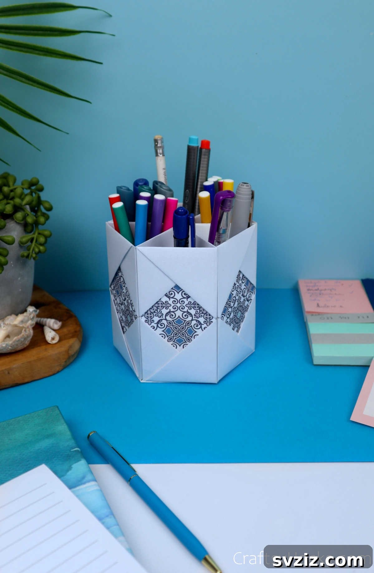 Completed DIY paper pencil holder sitting neatly on a clean wooden desk, filled with pens and pencils, indicating excellent desk organization.