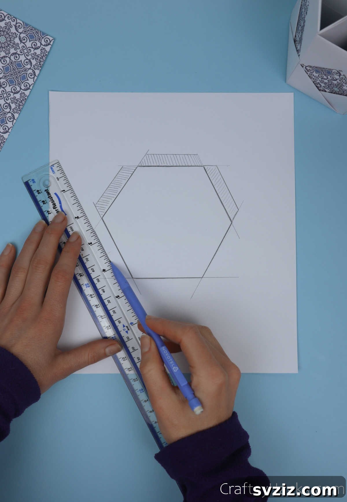 The traced hexagonal base outline with additional lines drawn around its perimeter, indicating where the crucial overlap flaps should be for secure attachment.