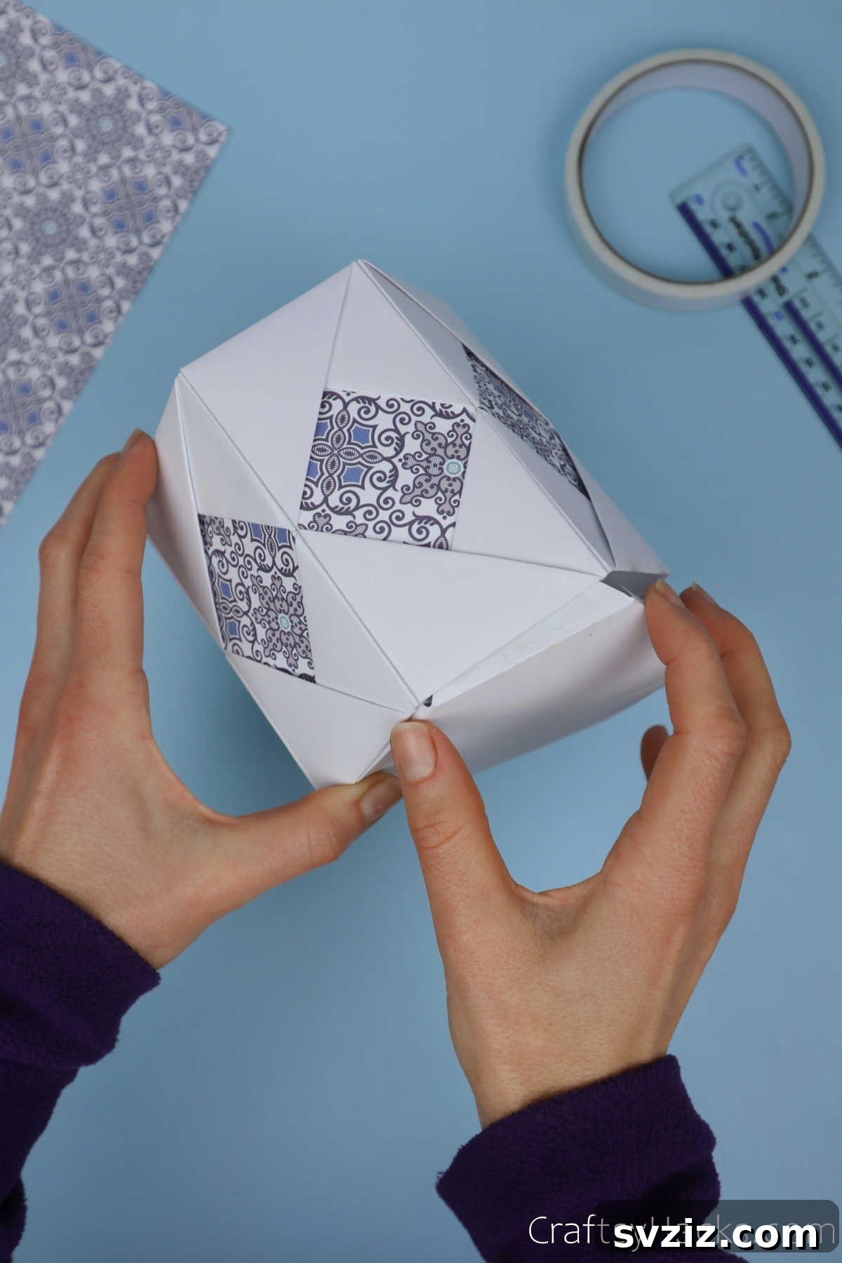 The hexagonal base being carefully inserted into the bottom opening of the assembled paper pencil holder, ensuring a perfect and snug fit.