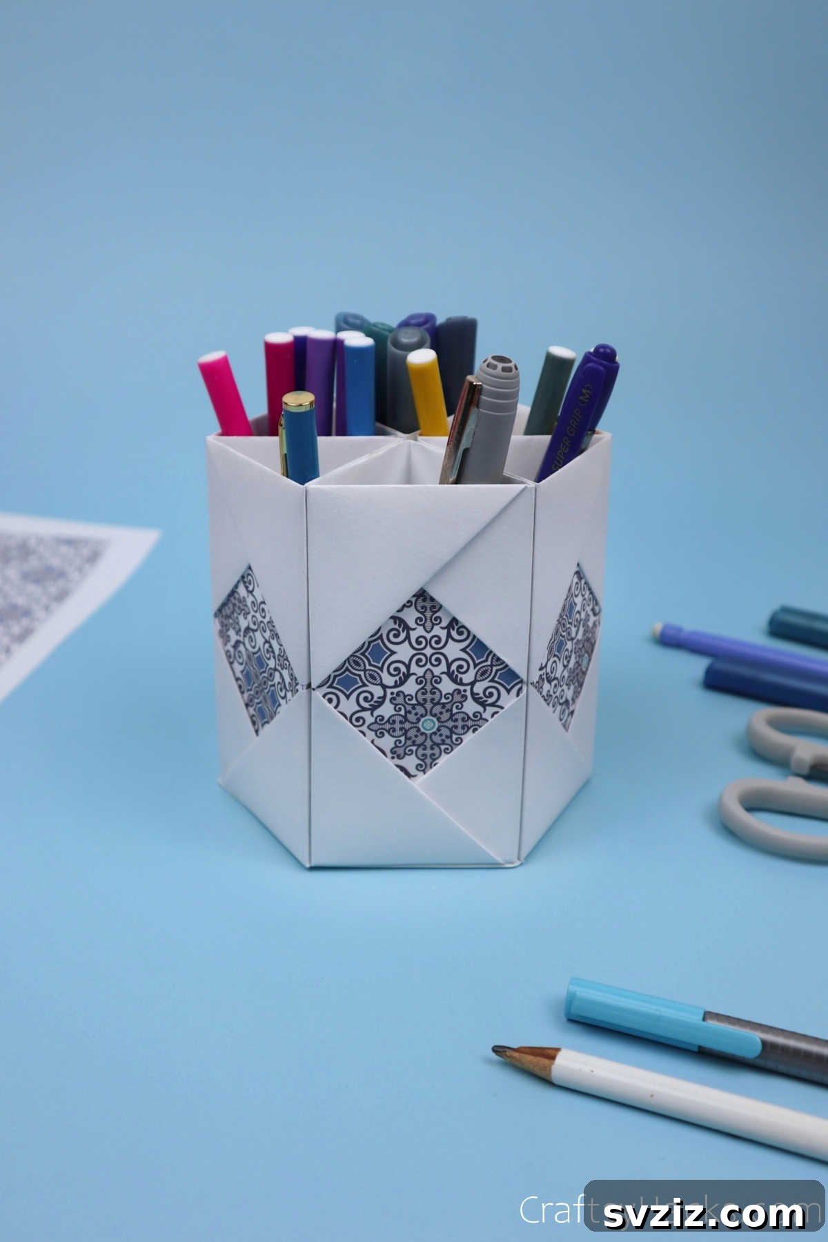 The completed DIY paper pencil holder, beautifully designed and filled with colorful pens and pencils, sitting elegantly on a clean desk.