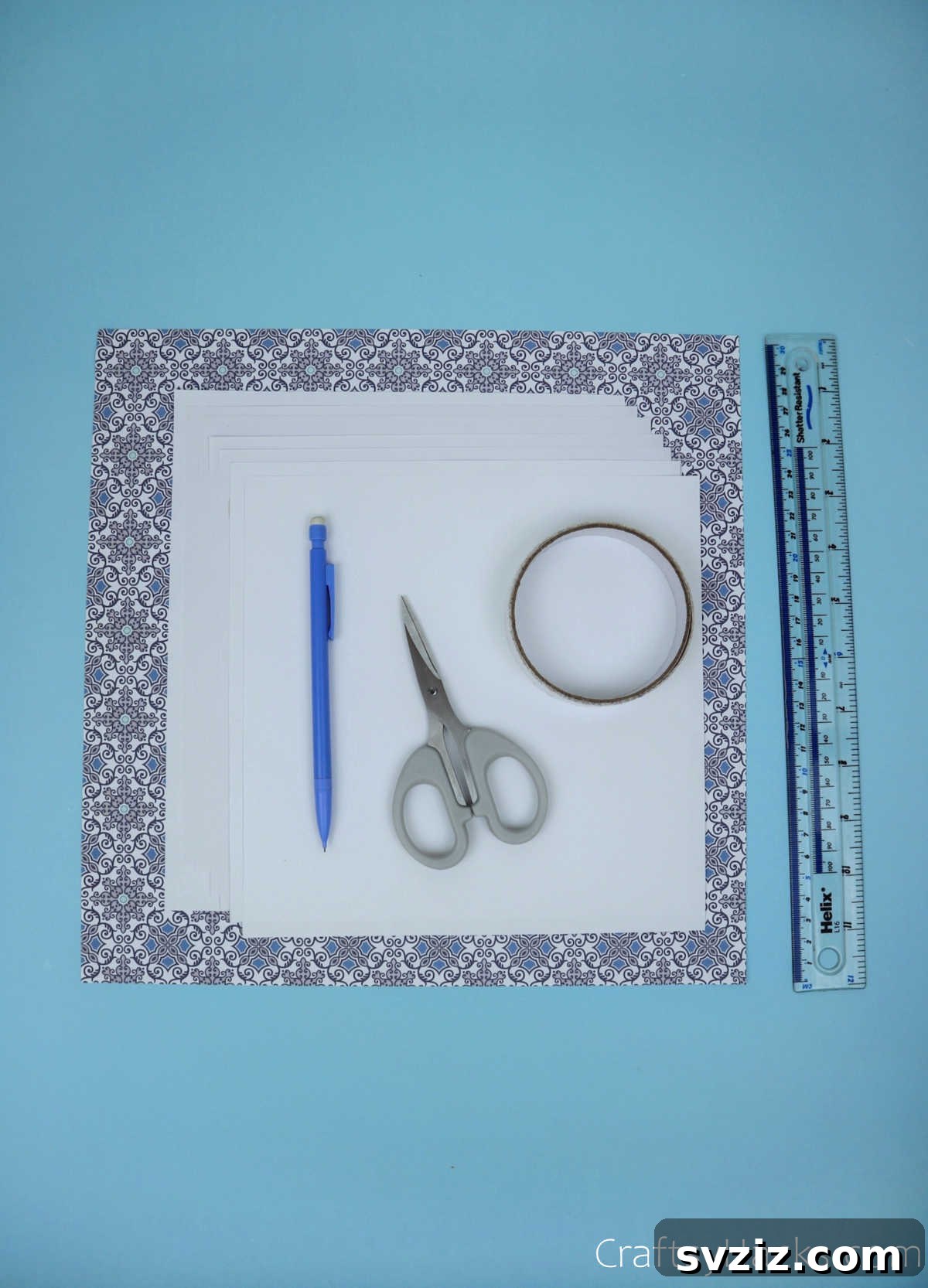 Various essential craft supplies neatly arranged on a flat surface, including square paper sheets, scissors, a ruler, and a glue stick, all ready for the DIY paper craft project.