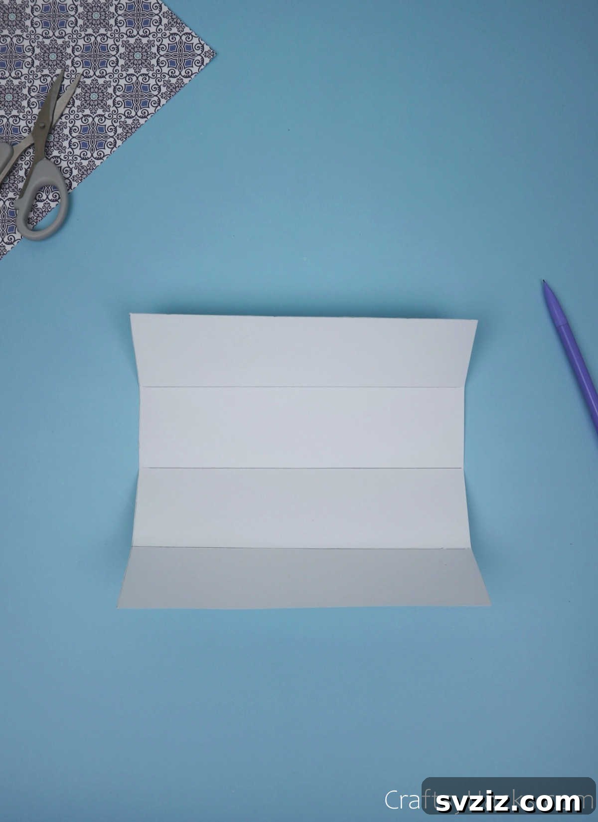 An unfolded paper sheet clearly showing three distinct horizontal creases, dividing the paper into four equally sized segments, foundational for grid creation.