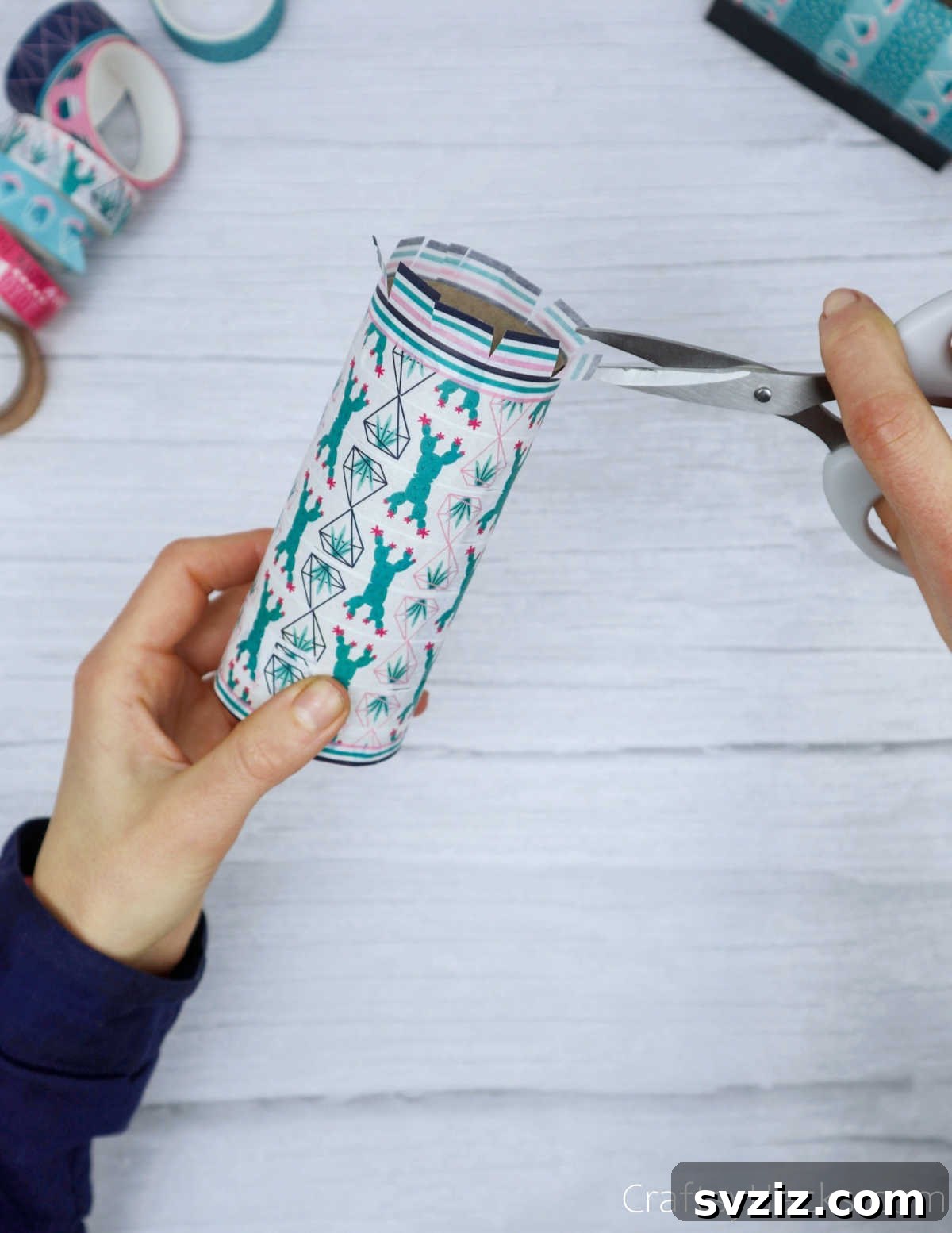 Roll Your Own Phone Stand from a Toilet Paper Tube 12 Scissors cutting small flaps into the overhanging washi tape around the rim of the paper roll.