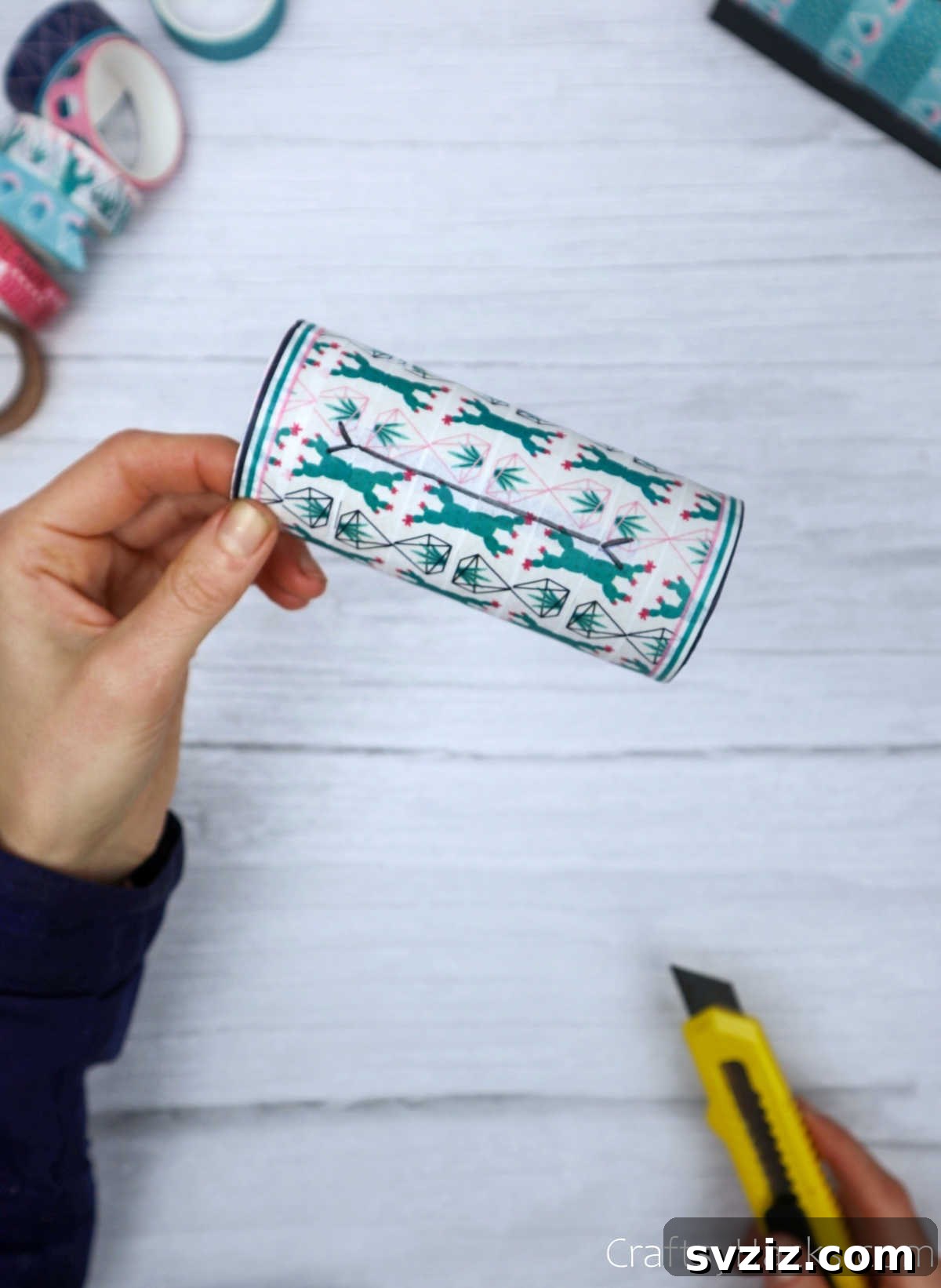 Roll Your Own Phone Stand from a Toilet Paper Tube 14 A craft cutter precisely slicing through washi tape covering the phone slot, revealing the underlying hole.
