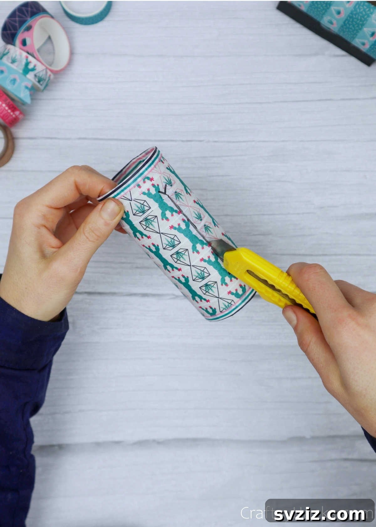 Roll Your Own Phone Stand from a Toilet Paper Tube 15 A detailed shot of a craft cutter making precise cuts through the washi tape, demonstrating the technique for a clean slot.