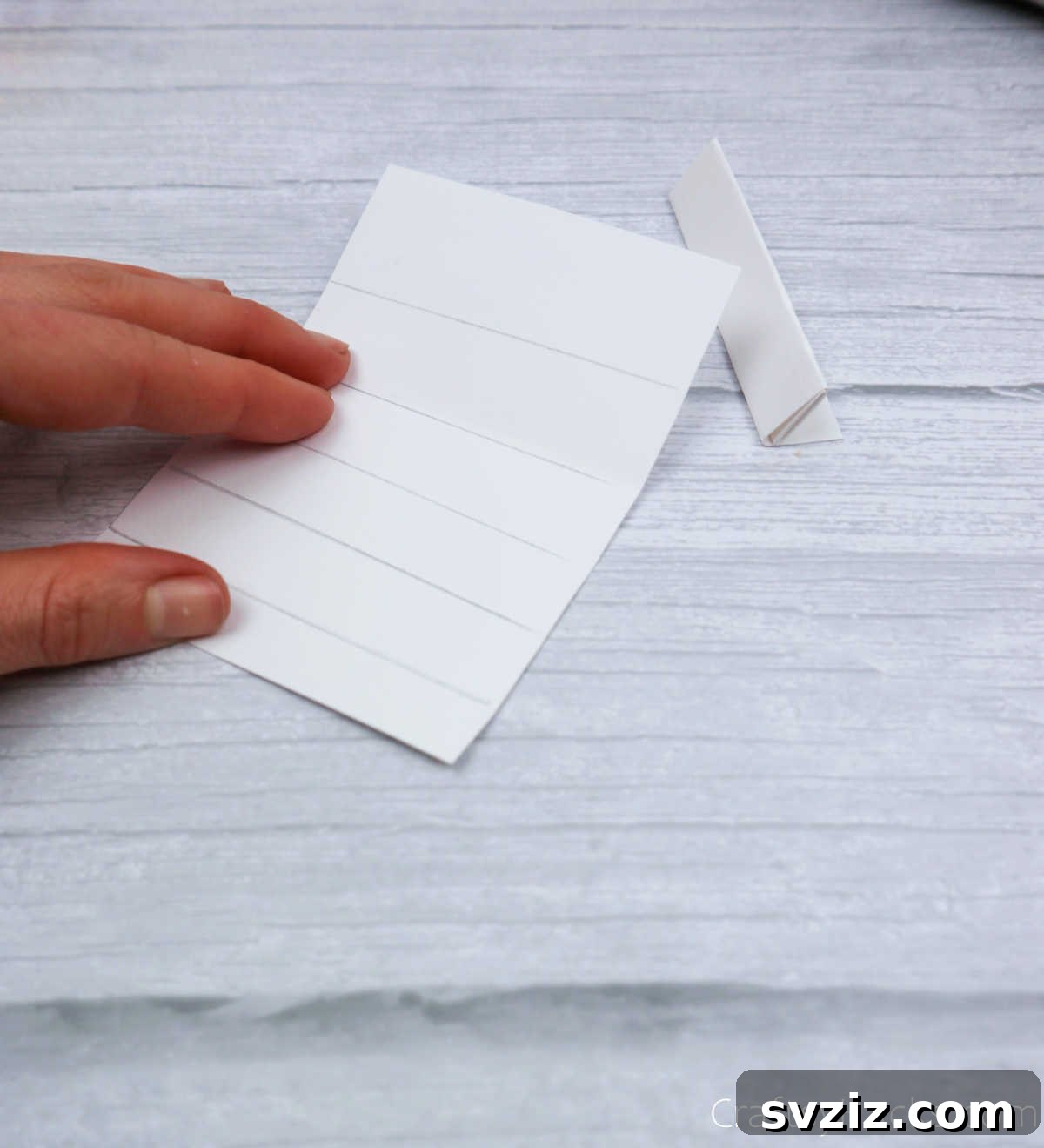 Roll Your Own Phone Stand from a Toilet Paper Tube 19 A piece of paper clearly folded into six equal sections, demonstrating the preparation for leg construction.