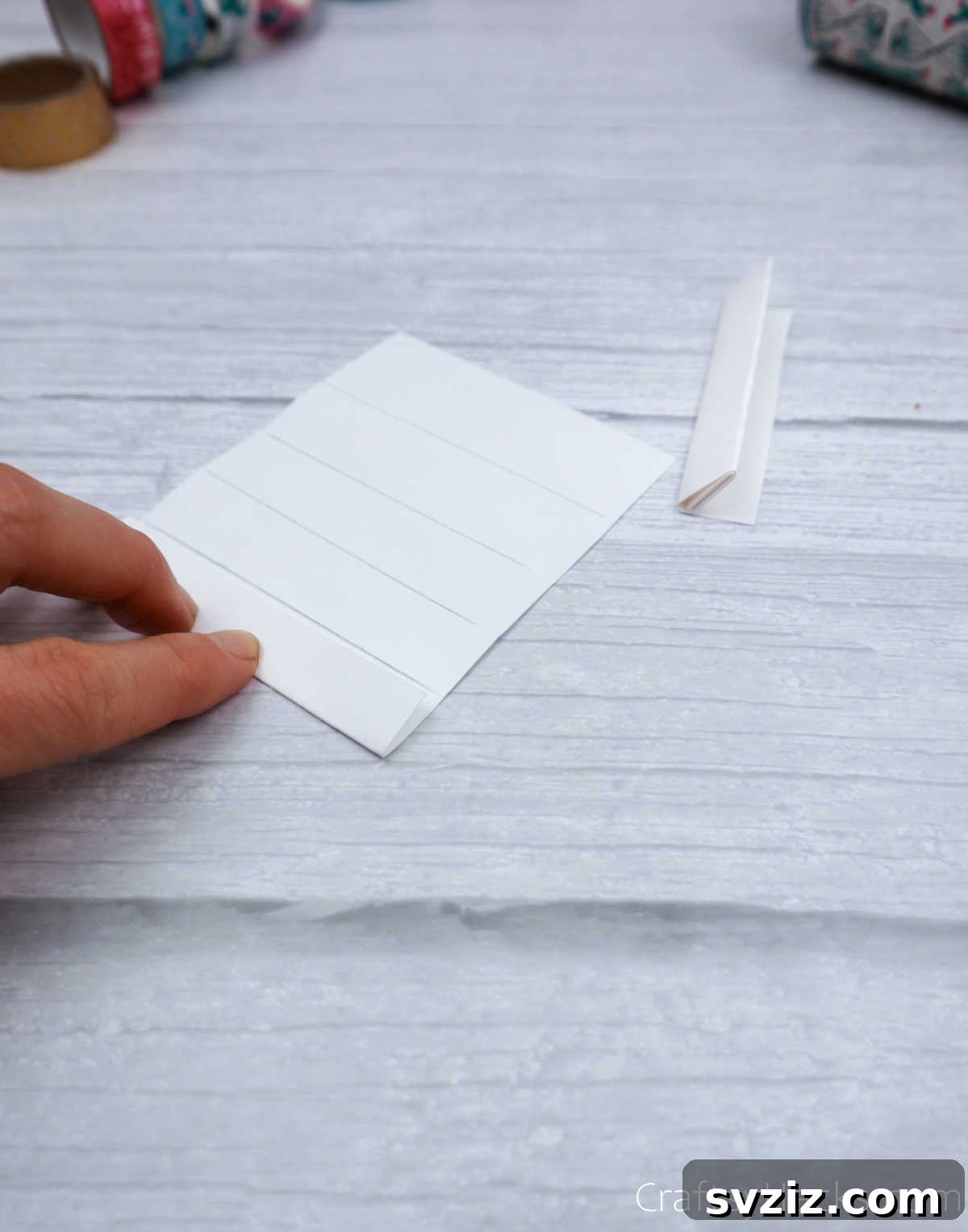 Roll Your Own Phone Stand from a Toilet Paper Tube 20 A paper strip being folded in an accordion pattern, showcasing the creation of creases for the legs.