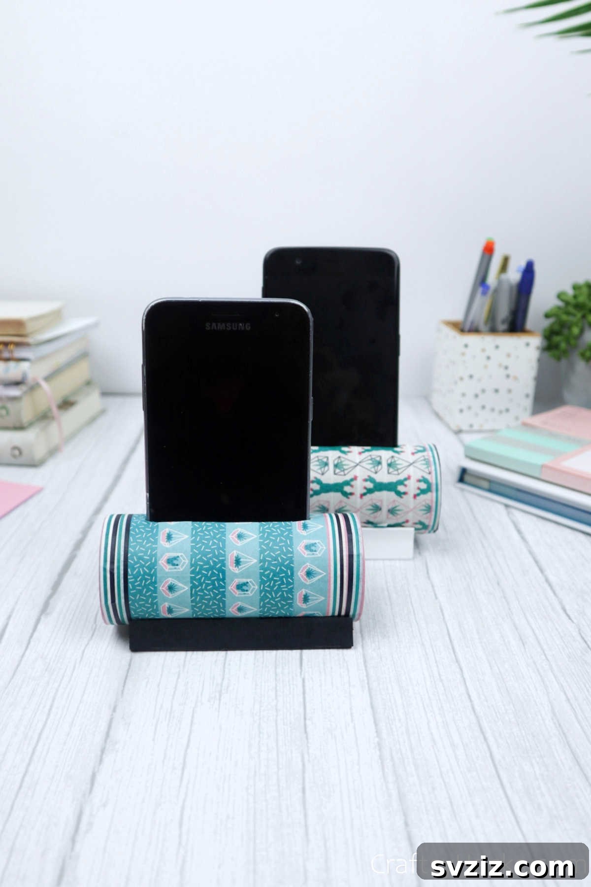 Roll Your Own Phone Stand from a Toilet Paper Tube 28 Two finished DIY phone holders, each with a phone resting securely in its slot, demonstrating practical use.