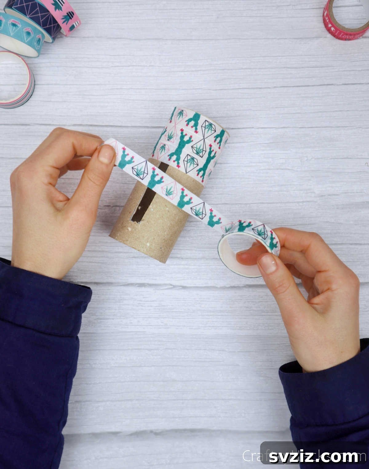 Roll Your Own Phone Stand from a Toilet Paper Tube 9 Hands carefully wrapping decorative washi tape around the exterior of a toilet paper roll.