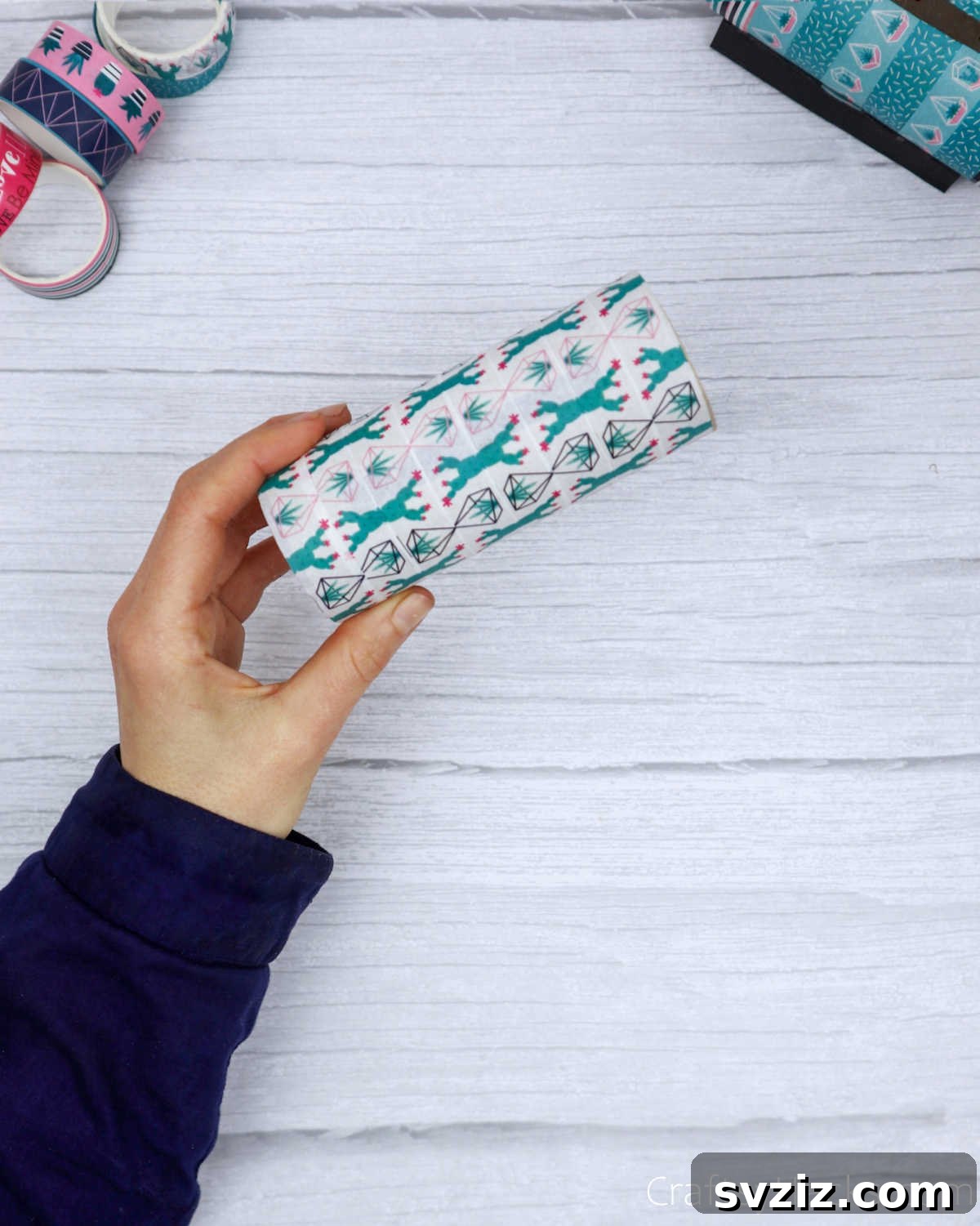 Roll Your Own Phone Stand from a Toilet Paper Tube 10 A toilet paper roll fully wrapped with colorful washi tape, showcasing a lively decorative pattern.