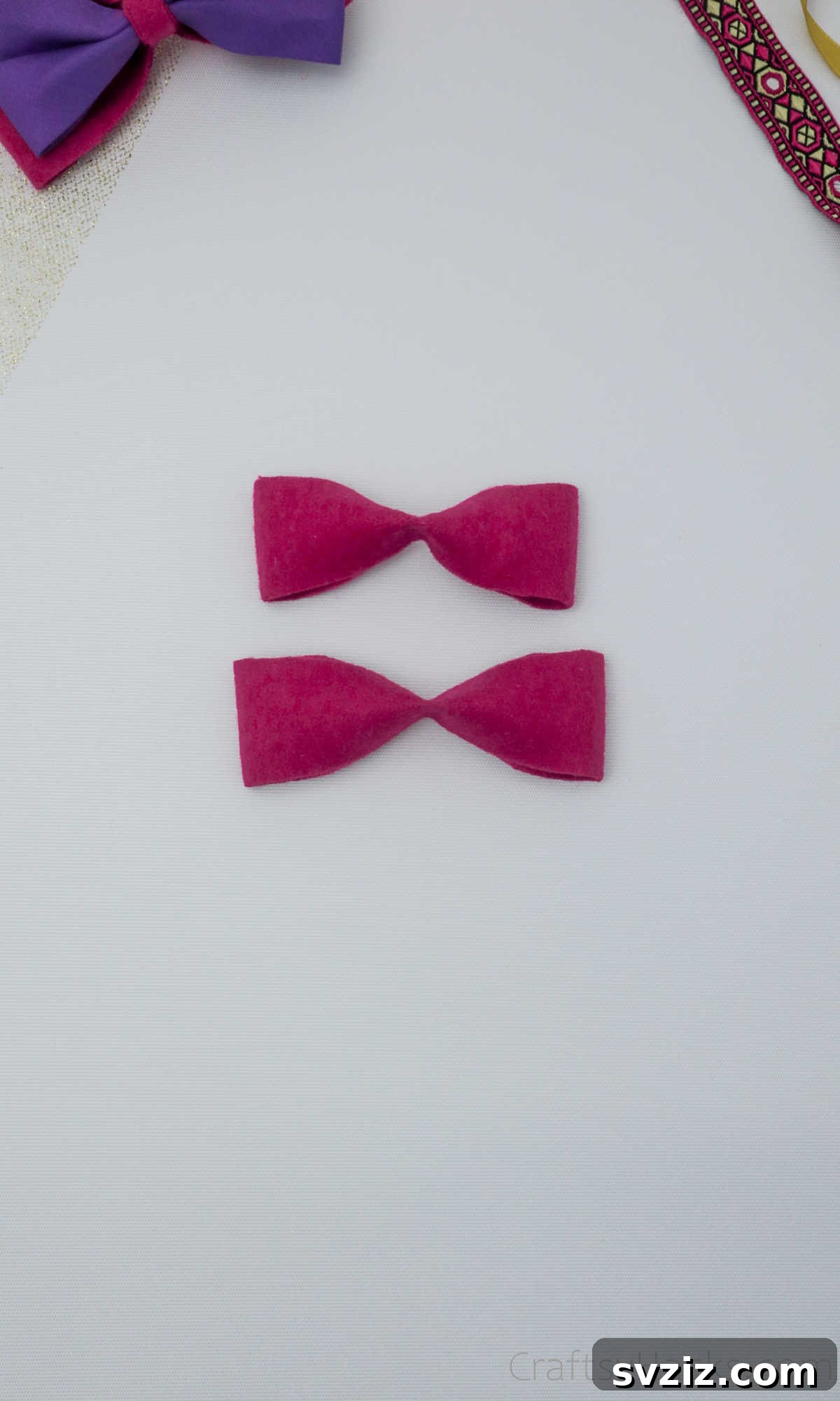 Two expertly pinched pink felt bows, showcasing their enhanced shape and readiness for further assembly
