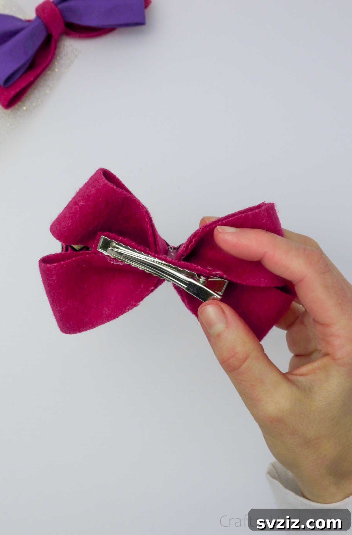 The final moments of gluing the hair clip to the bow, ensuring a strong and lasting attachment for the handmade accessory