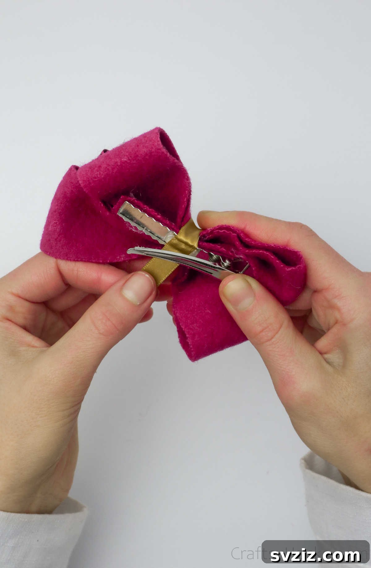 The yellow ribbon securely wrapped around the crocodile clip, ensuring the bow is firmly attached and beautifully finished