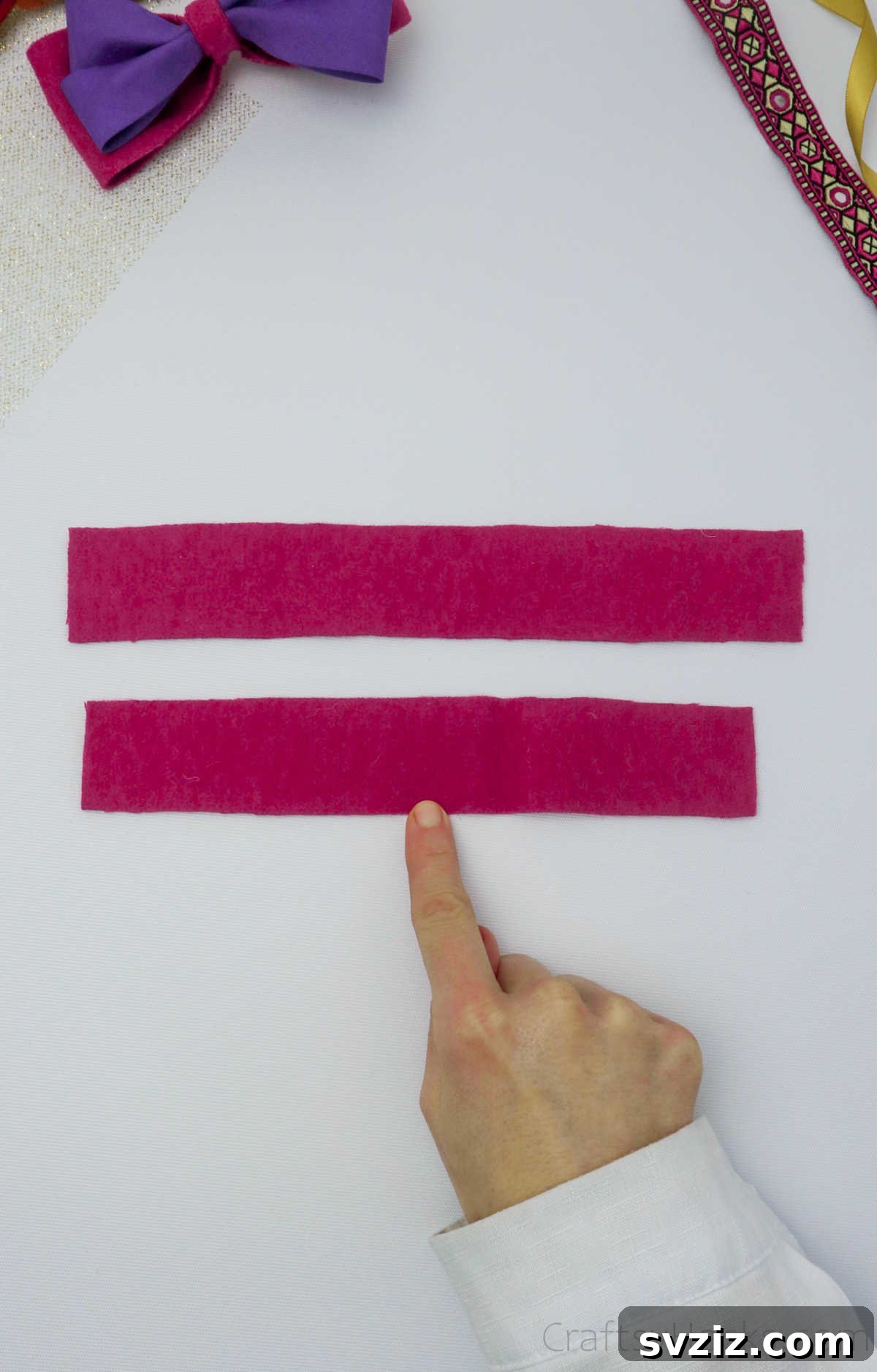 Two neatly laid out pink felt strips on a flat surface, illustrating the first step in bow making