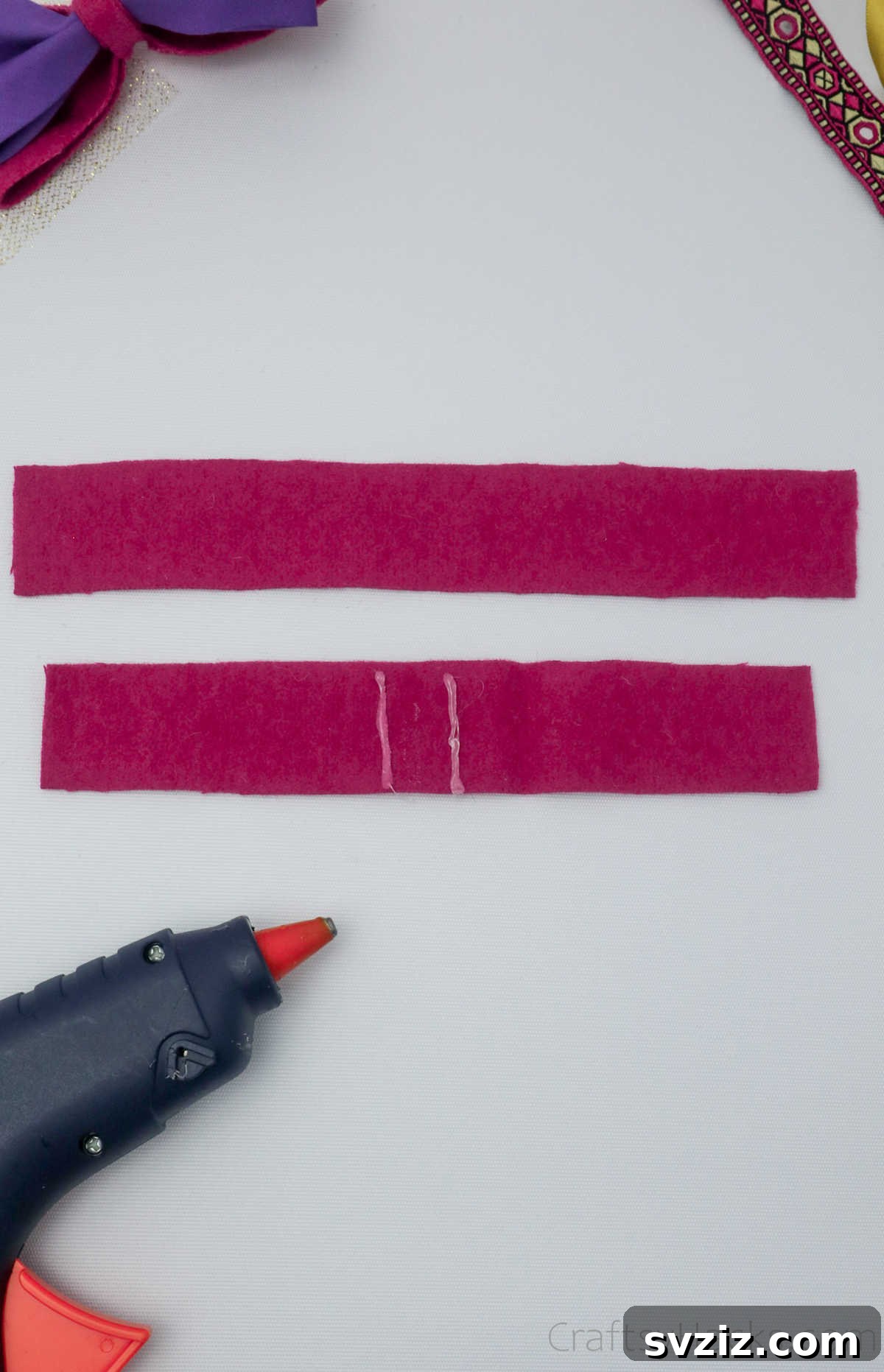 Hot glue applied to the center of a folded pink felt piece, illustrating the precise adhesion method