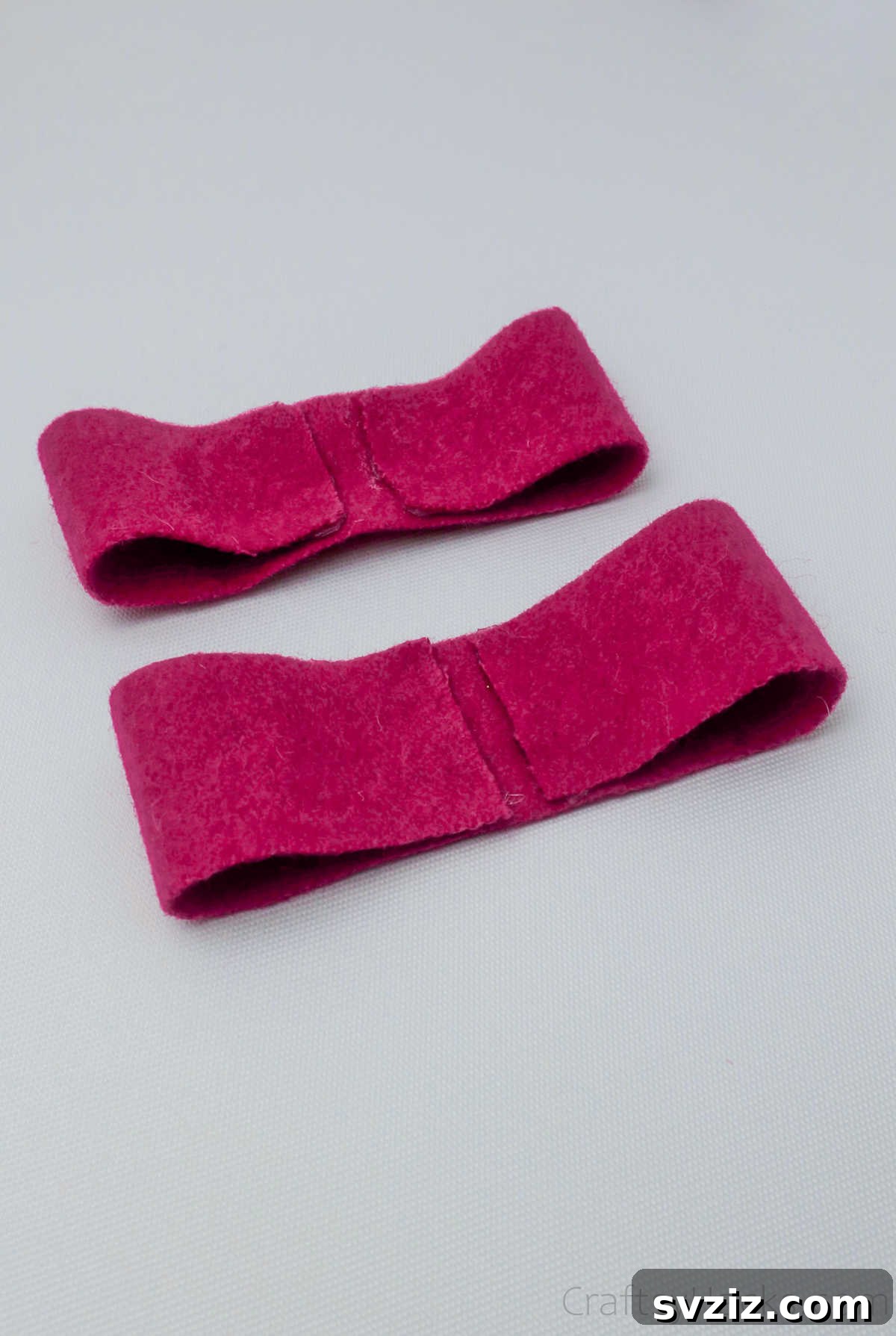 Two perfectly shaped pink felt bow pieces, ready to be assembled into a layered hair bow