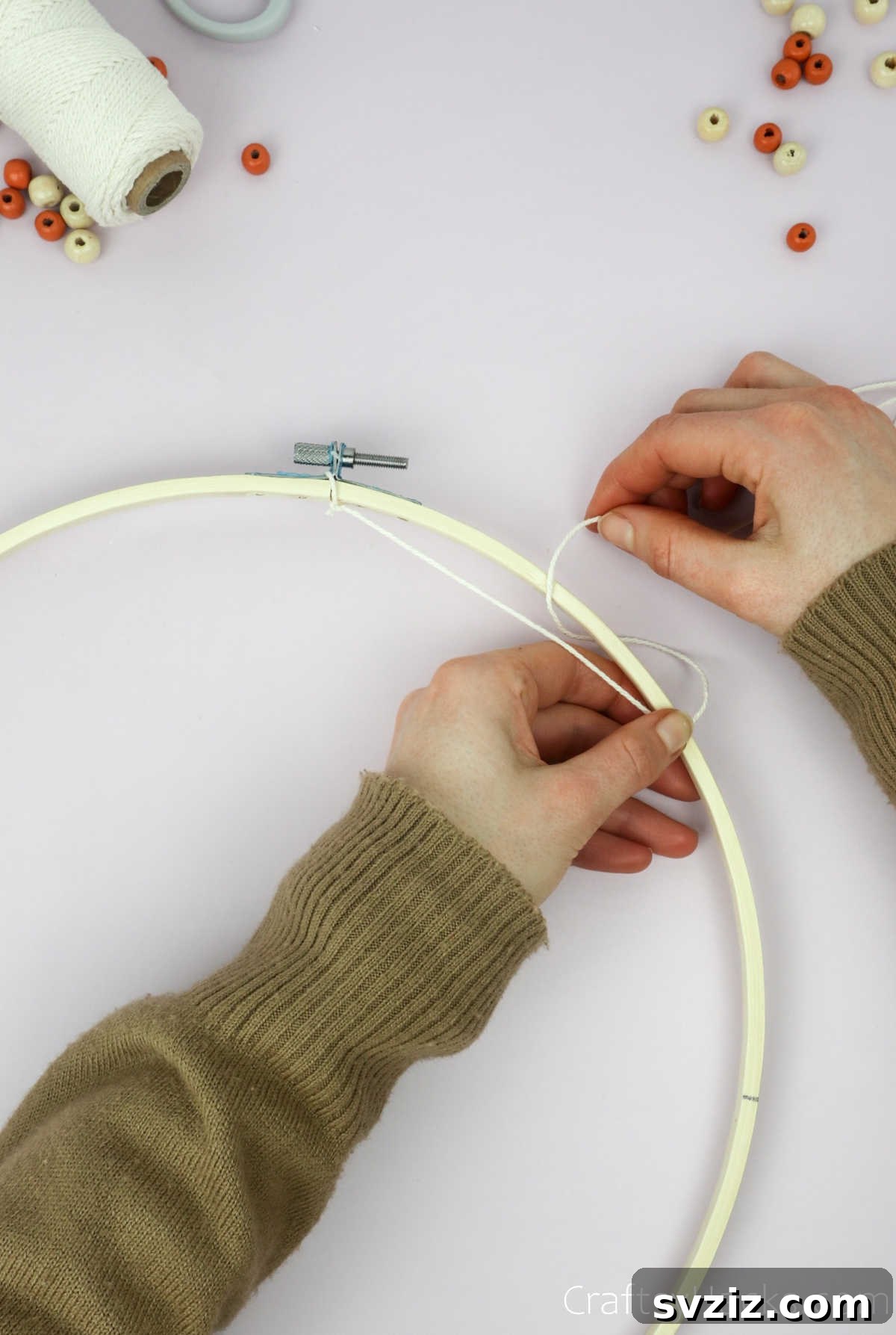 From Clutter to Charm: DIY Jewelry Storage 11 A close-up shot showing the beige cotton string successfully looped around the embroidery hoop, forming the initial anchor for the dreamcatcher pattern.