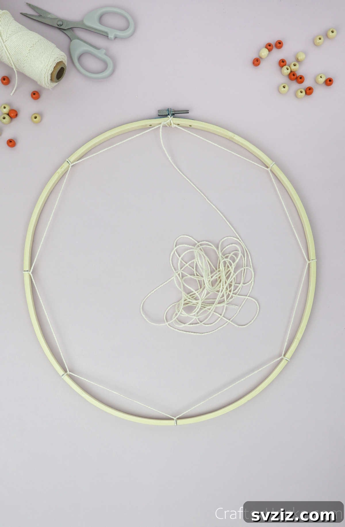 From Clutter to Charm: DIY Jewelry Storage 16 The initial round of weaving is complete, with beige cotton string looped all the way around the embroidery hoop, forming the outermost ring of the dreamcatcher web.