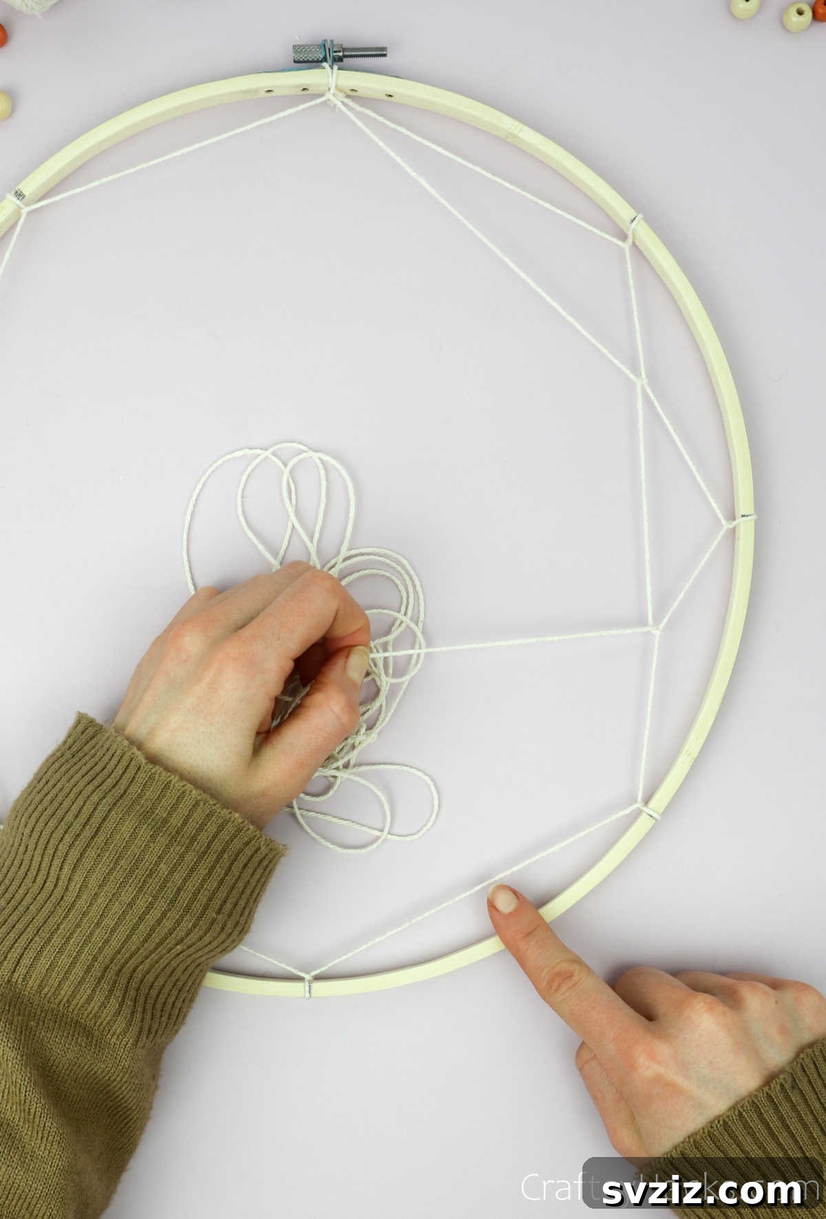 From Clutter to Charm: DIY Jewelry Storage 18 A close-up showing the beige cotton string neatly looped around a segment of the first string layer, demonstrating the technique for the inner rounds of the dreamcatcher web.