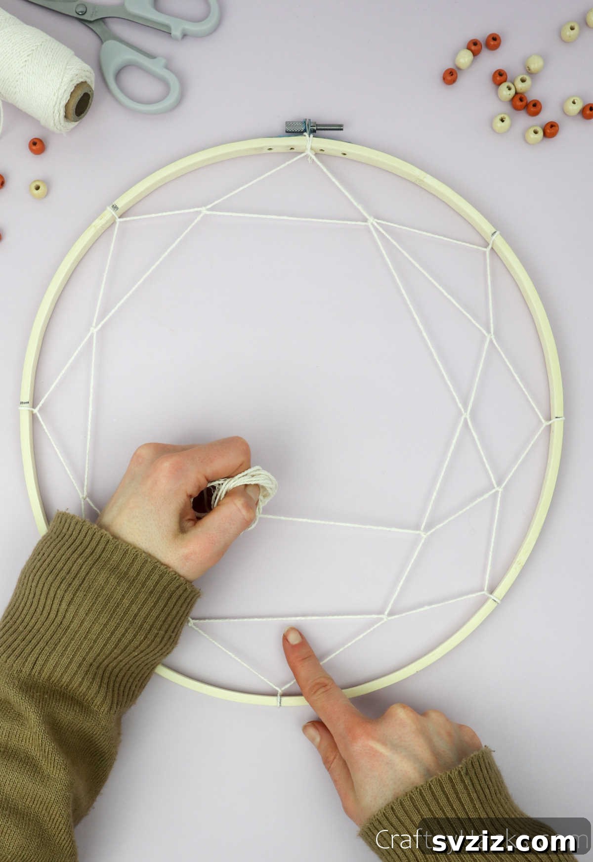 From Clutter to Charm: DIY Jewelry Storage 22 The dreamcatcher web is progressing, showing multiple concentric layers of beige cotton string meticulously wrapped around the embroidery hoop, creating a dense pattern.