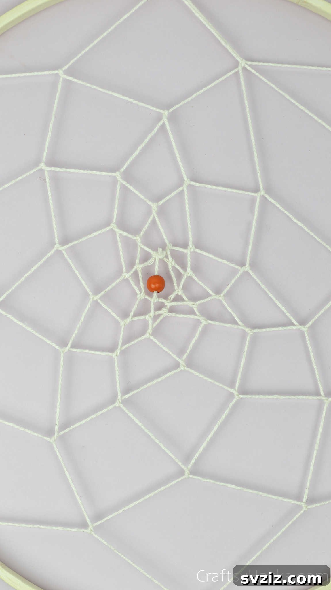 From Clutter to Charm: DIY Jewelry Storage 27 The completed center of the dreamcatcher web, featuring a small bead neatly integrated into the final knot, creating a polished and decorative focal point.