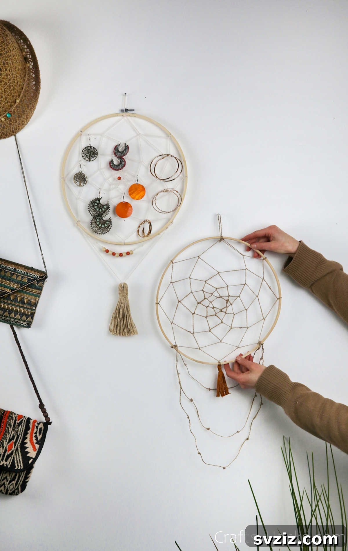 From Clutter to Charm: DIY Jewelry Storage 4 A single DIY dreamcatcher jewelry organizer hanging on a textured wall, beautifully displaying a variety of earrings and necklaces. The intricate white string web within the wooden hoop creates multiple hanging points for accessories.