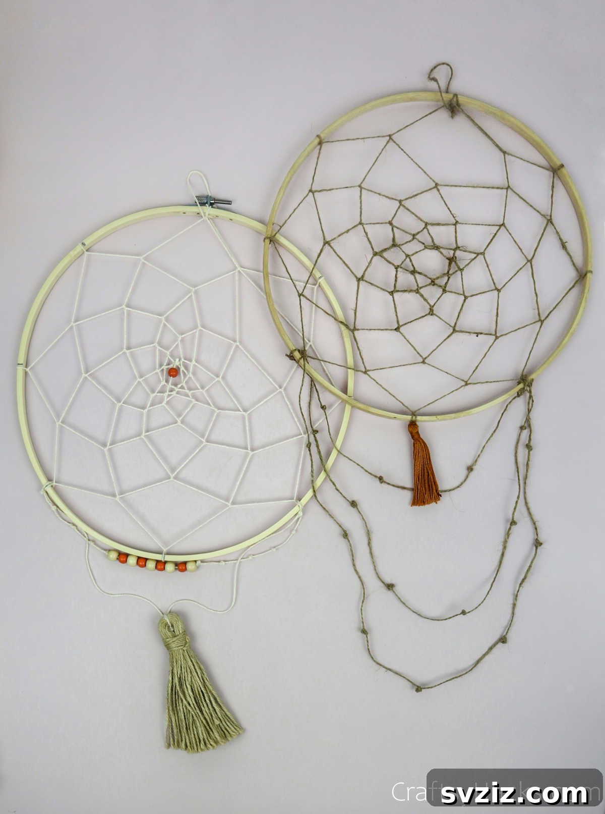 From Clutter to Charm: DIY Jewelry Storage 36 A pair of finished DIY dreamcatcher jewelry organizers, one with a subtle beige and white string web and the other with a classic white web, showcasing their handcrafted appeal.