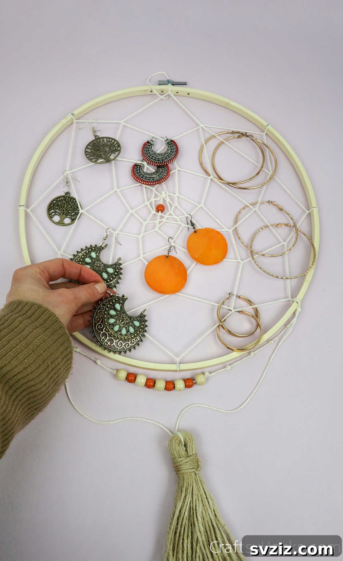 From Clutter to Charm: DIY Jewelry Storage 37 A close-up of a DIY dreamcatcher jewelry organizer displaying an array of earrings, with their hooks neatly caught in the intricate string web, making them easily accessible and visible.