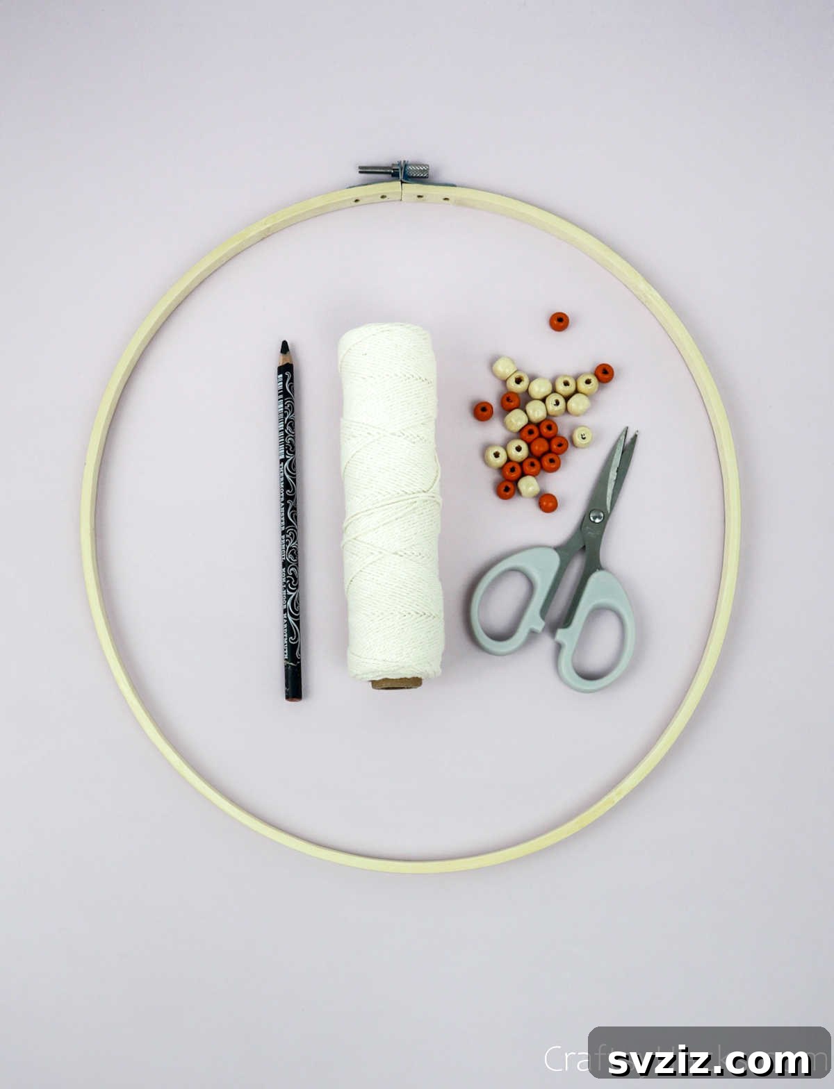 From Clutter to Charm: DIY Jewelry Storage 5 A collection of craft supplies including an embroidery hoop, a spool of cotton string, and a small pile of colorful beads, neatly arranged on a white surface, ready for a DIY project.