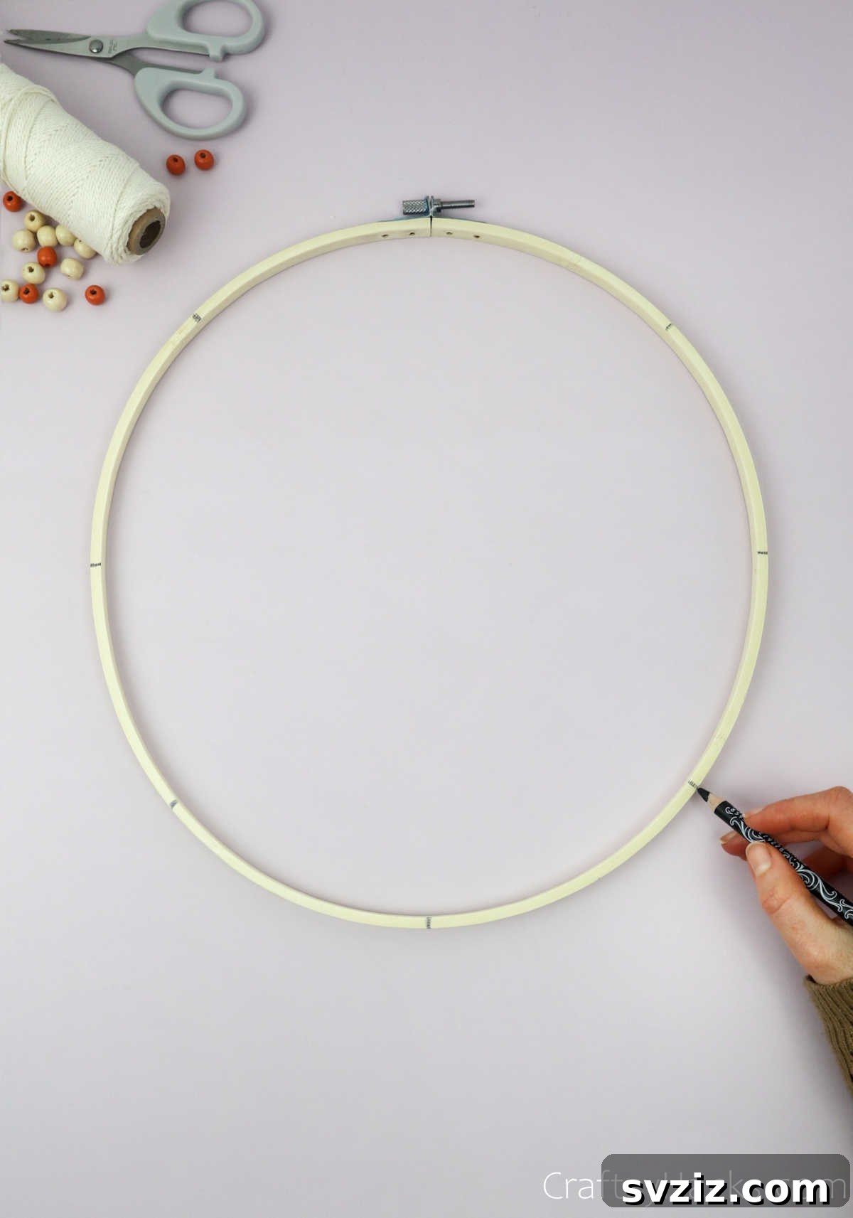 From Clutter to Charm: DIY Jewelry Storage 7 An embroidery hoop with eight evenly spaced pencil marks around its perimeter, indicating the points where the string will be tied.