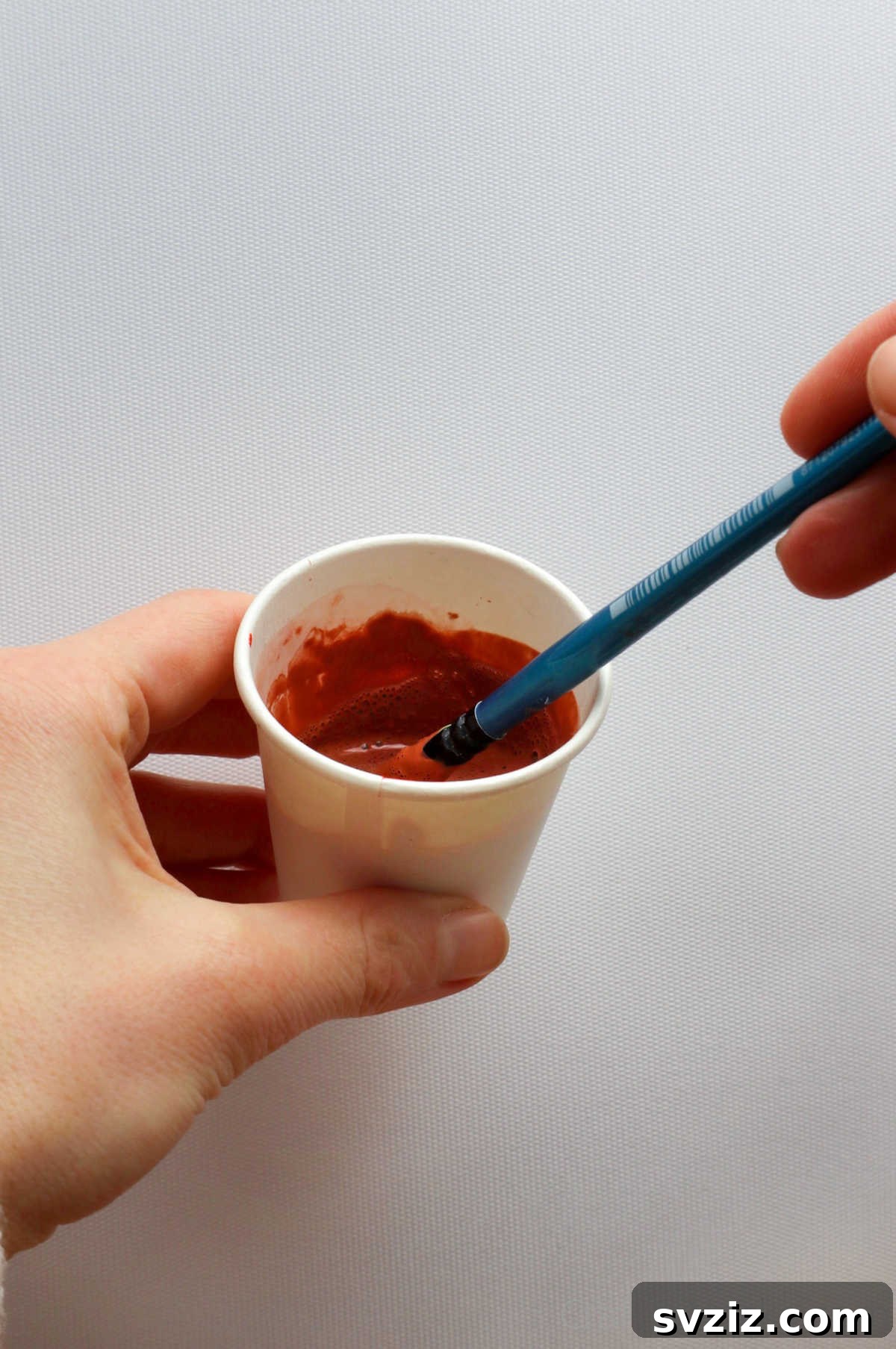 Orange acrylic paint in a small cup for bottle decorating