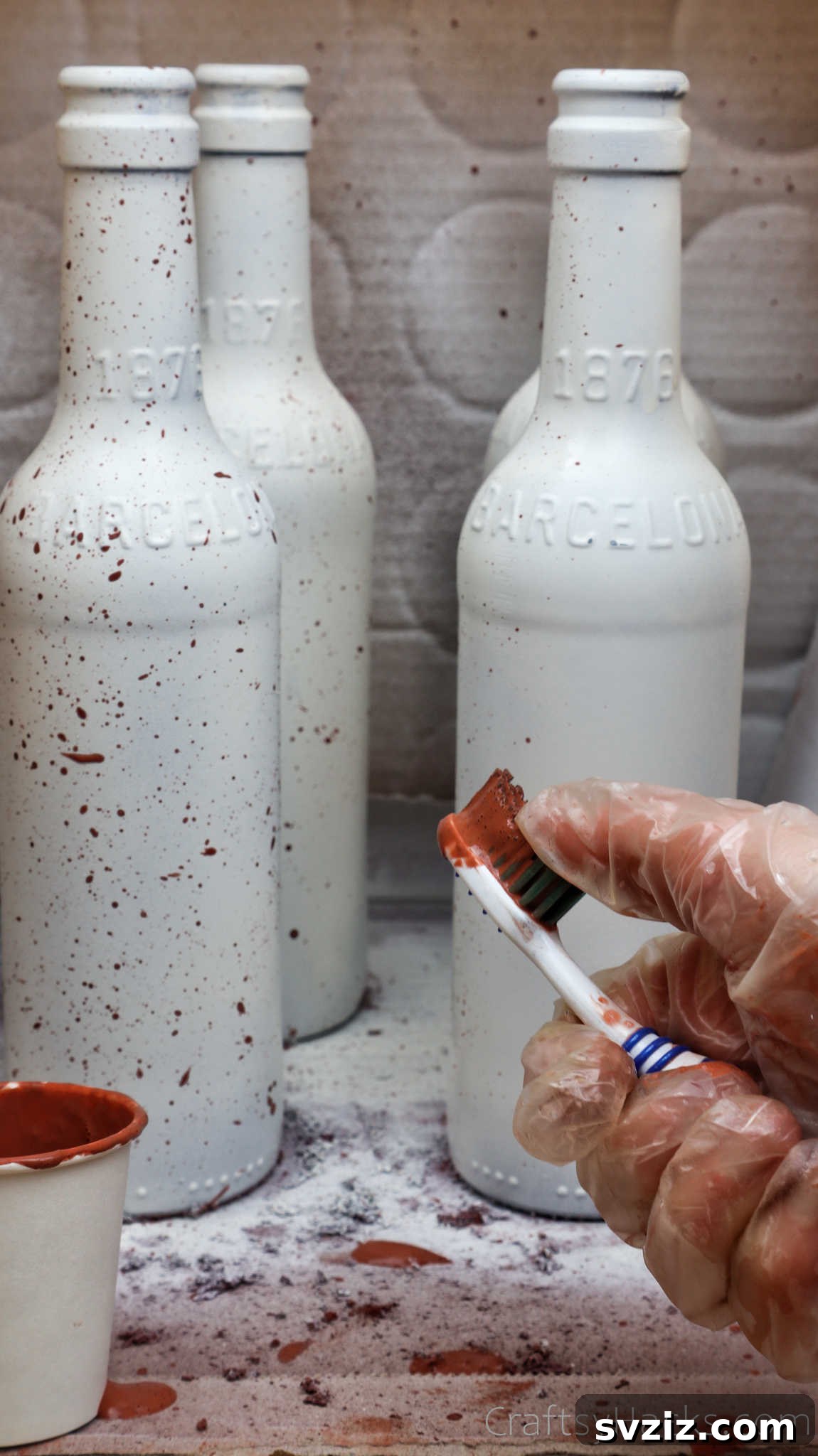 Splattering paint on a white bottle with a toothbrush