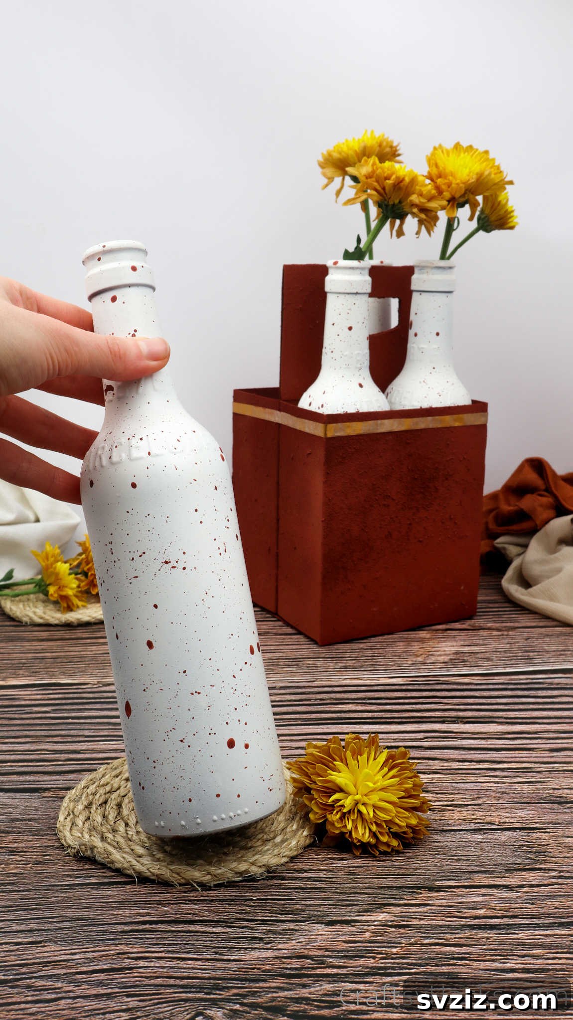 Holding a finished painted beer bottle from the DIY centerpiece project